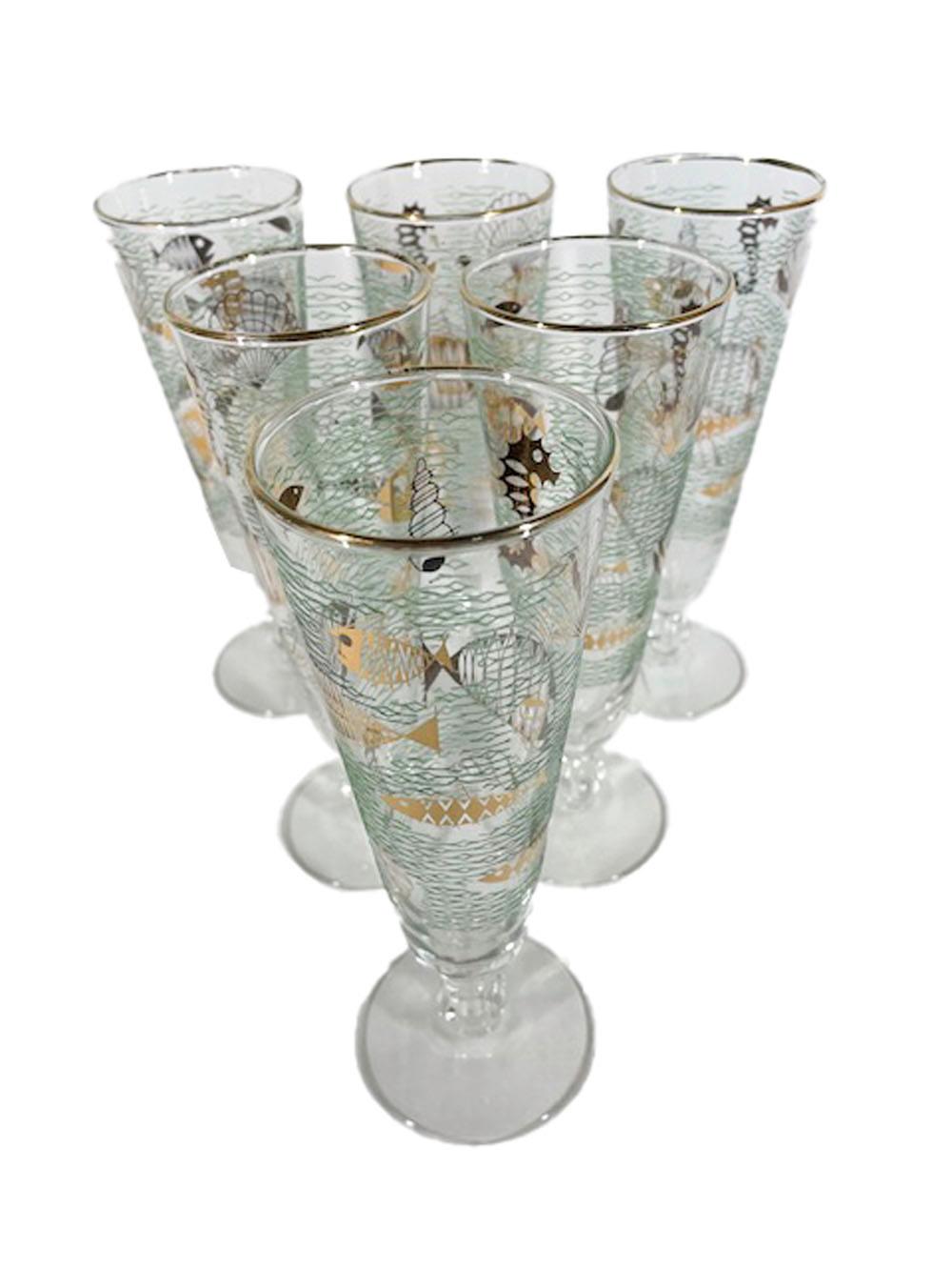 Six mid-century modern pilsner glasses in the Marine Life pattern by Libbey Glass Company, having a raised translucent green enamel wave patterned ground with 22k gold stylized fish and other sea creatures.