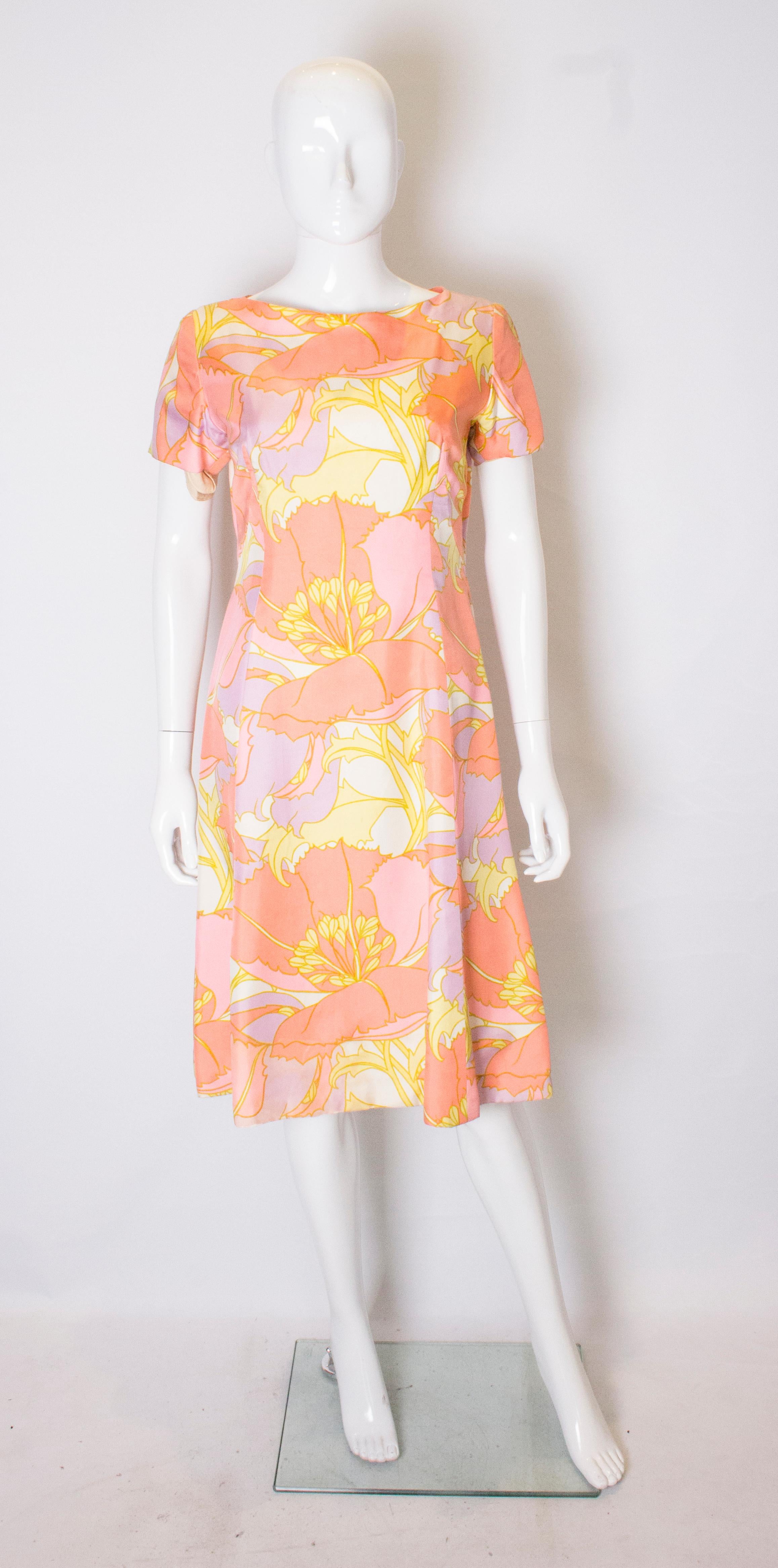 A beautifuly made vintage day dress in a pretty print of peach , yellow and lilac. The dress has short sleves , a round neckline, with a lower backline. It is fully lined and has a central back zip.