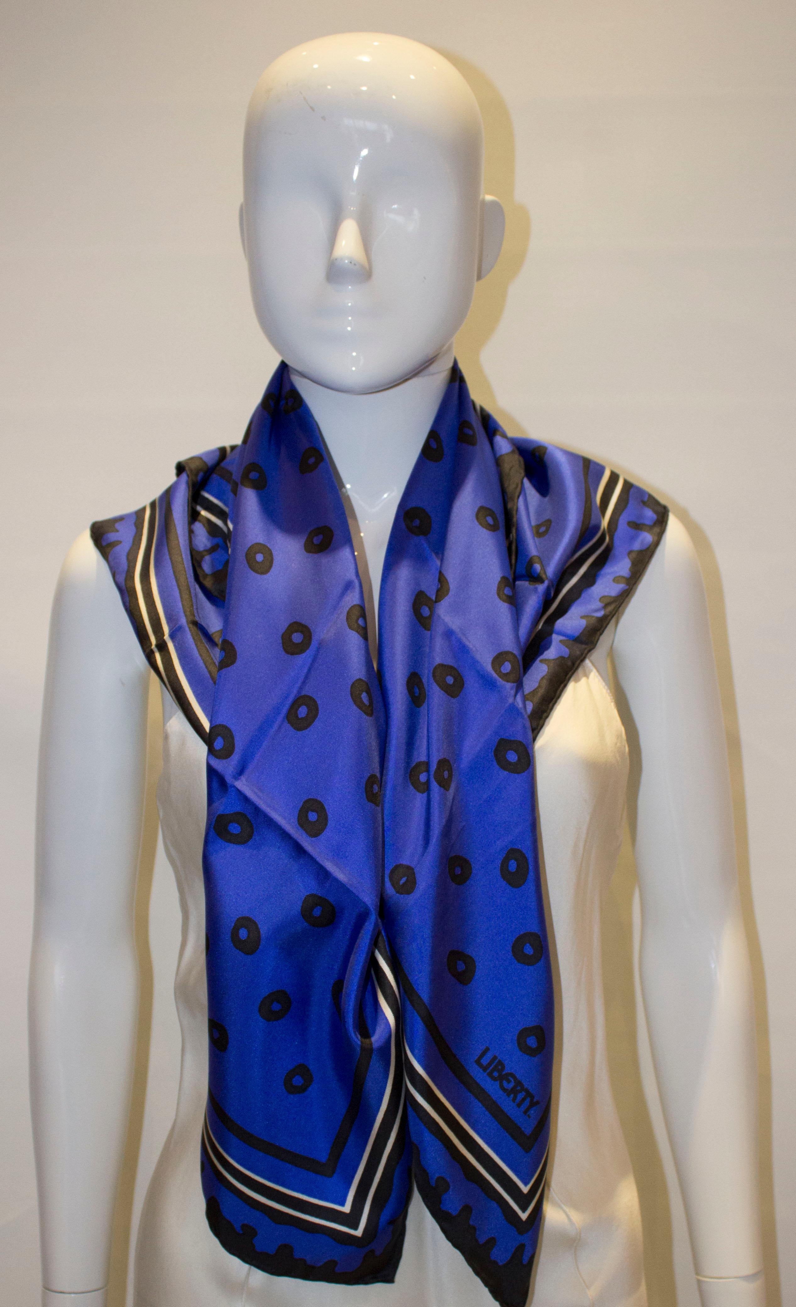 A super silk scarf by Liberty of London. The scarf is in a bleu silk with a black border, and measures 34'' square.