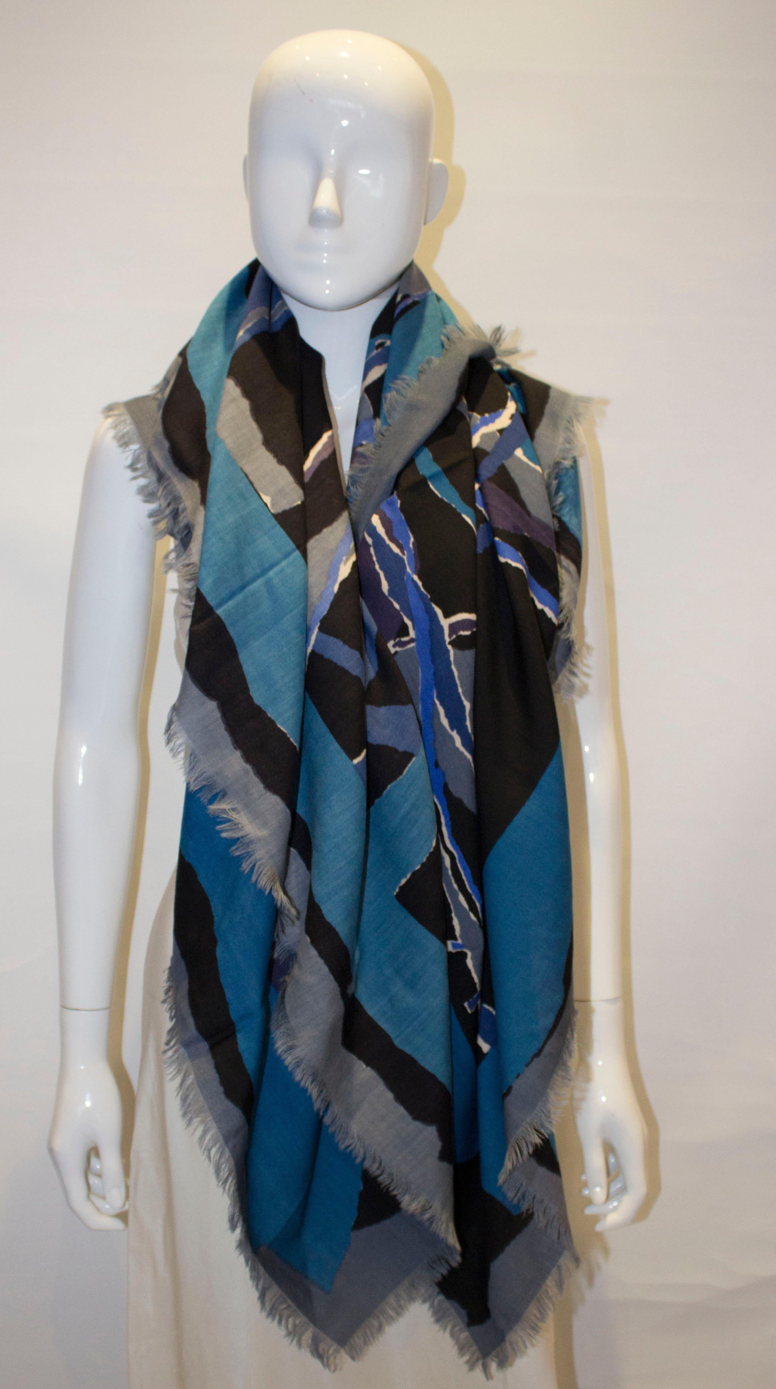  A wonderful and warm shawl by Liberty of London. In an abstract print of blue ,grey puprle and white with fringing. Measurement 53' square.