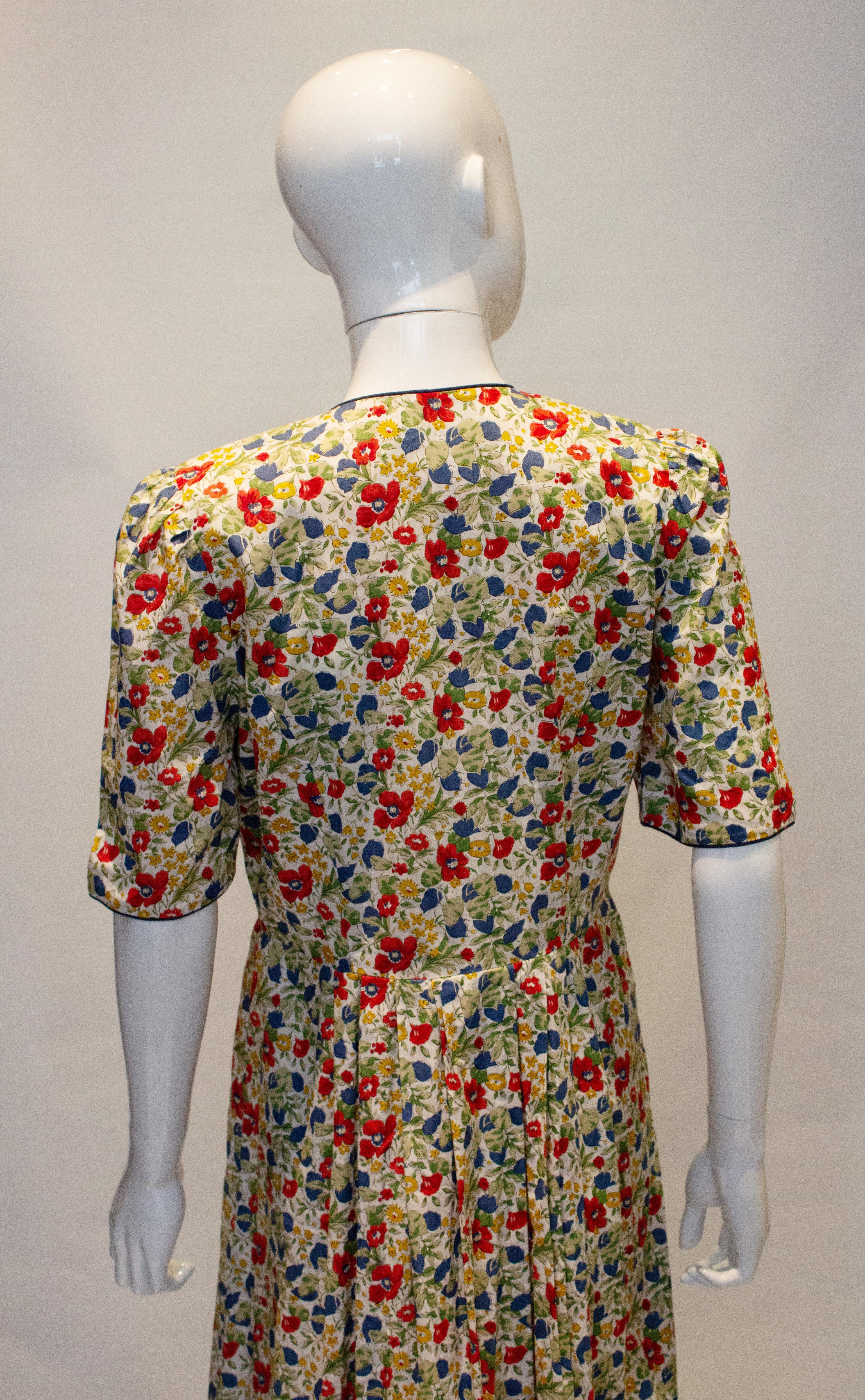 A pretty vintage cotton dress by Liberty.  The dress is in a floral print with as blue trim. It has a button from opening, with two pockets and pleats at the waist. 
Measurements : Bust up to 40'', waist 31'', length 50''