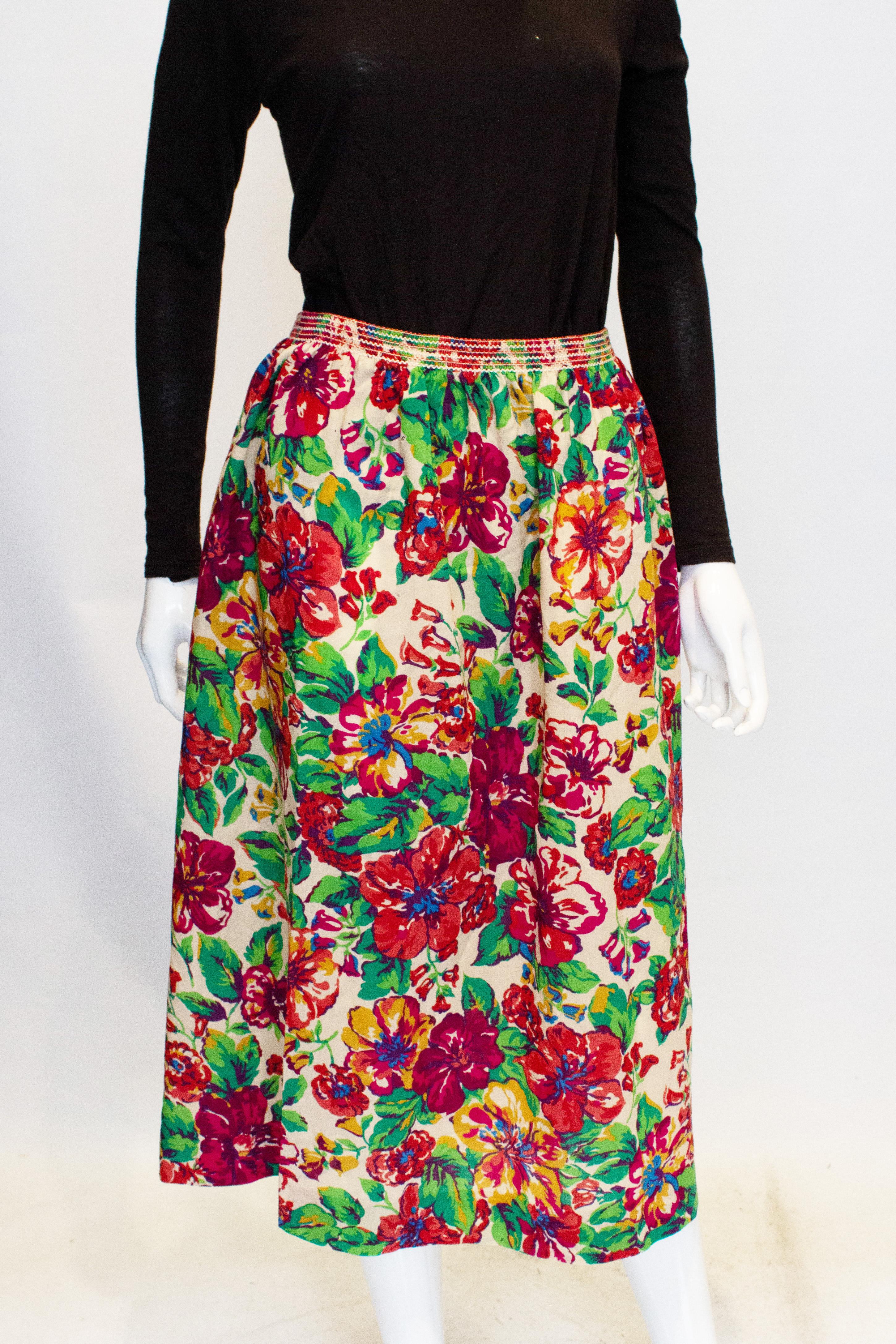 Une jolie jupe vintage en laine de Liberty of London.  La jupe a un fond crème avec un imprimé floral vert et violet. Il a une taille élastiquée, et conviendra à une taille de 27 - 32'', longueur 33''.