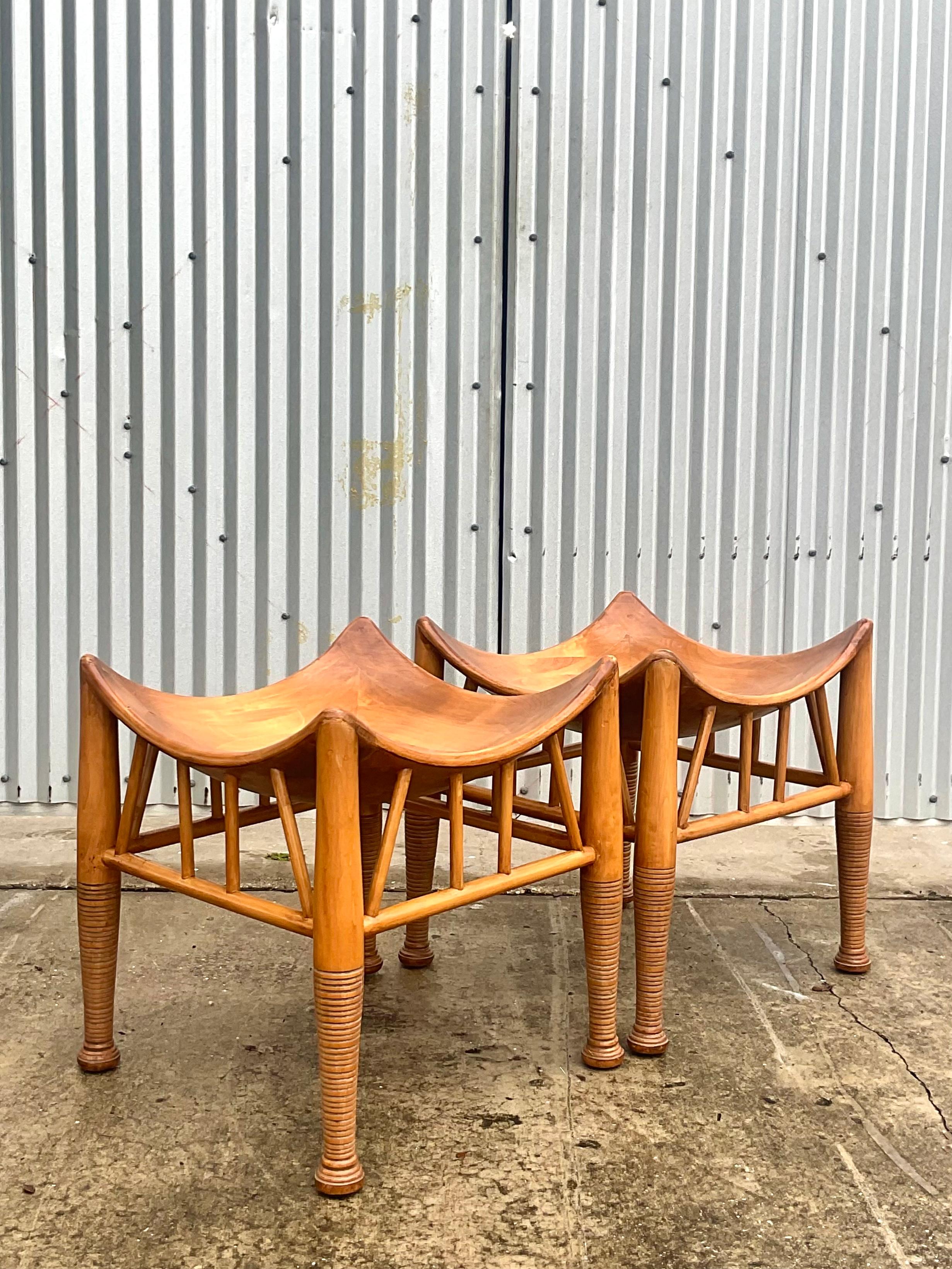 A fantastic pair of 1900s Liberty style Thebes stools. Hand crafted after classic Egyptian artifacts ans patented by Liberty and Co in 1884. Solid wood interlocking flared tops with classic stacked legs. Acquired from a Palm Beach estate.