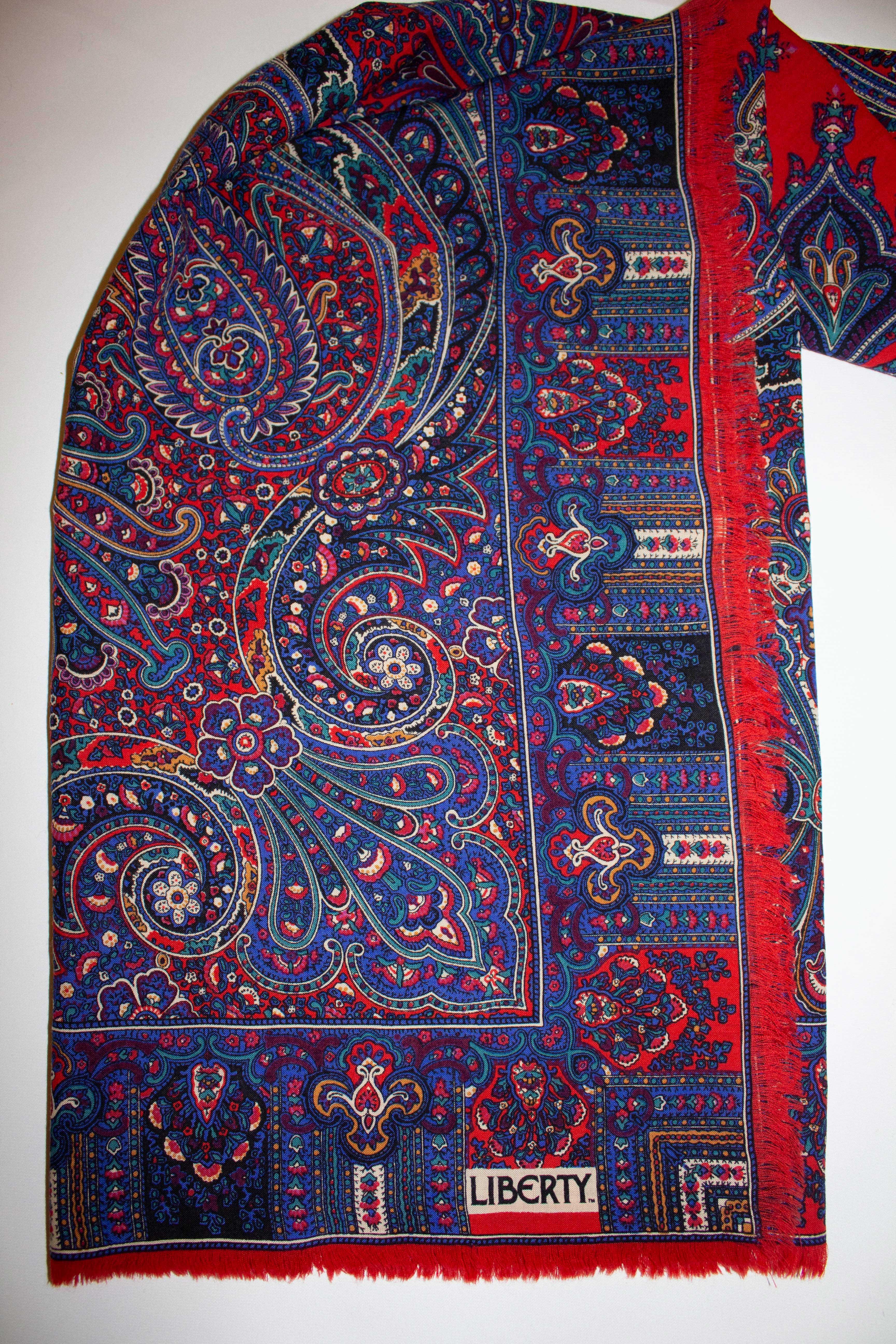 A wonderful , classic vintage Liberty of London wool scarf.  The scarf is in a red , blue , turquoise and lilac design with fringing. Measurements:  52'' x 52''