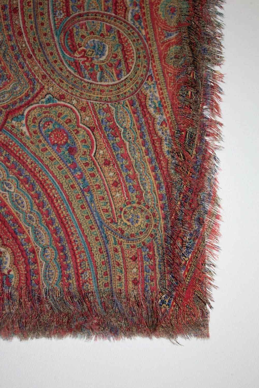 A wonderful vintage wool shawl by Liberty of London. The scarf  is in a red , turquoise, and blue paisley print with fringing at the ends . 100 % wool, made in England. Measurements: 53'' x 51''