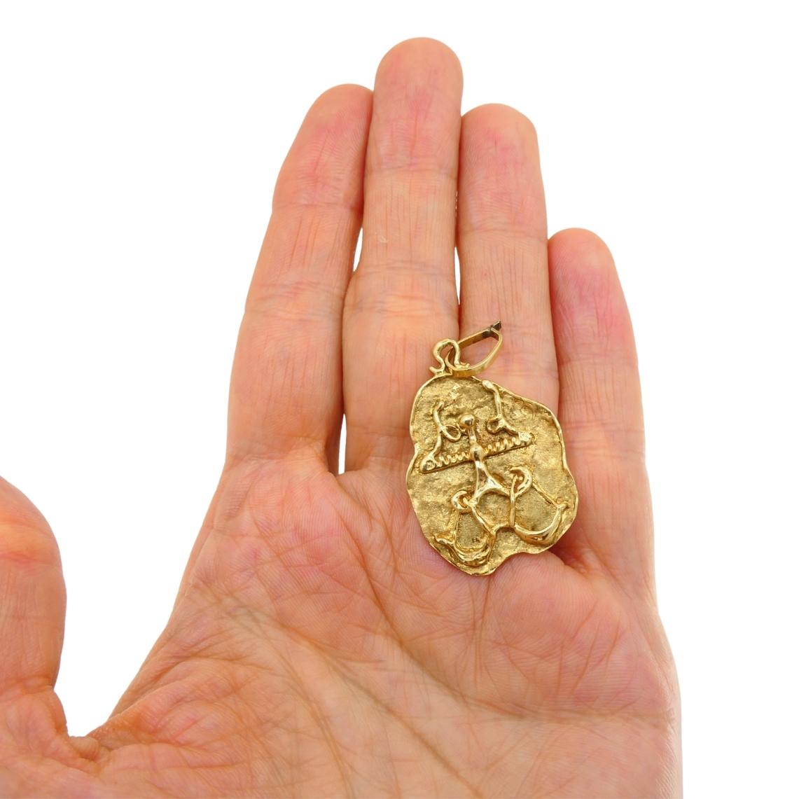 Pendentif Vintage Byhouette, en or 14k texturé avec une silhouette irrégulière. Le recto est gravé d'un jeu d'écailles stylisé, symbole du signe zodiacal de la Balance, tandis que le verso est un or poli avec une surface texturée et gravée. 
Le