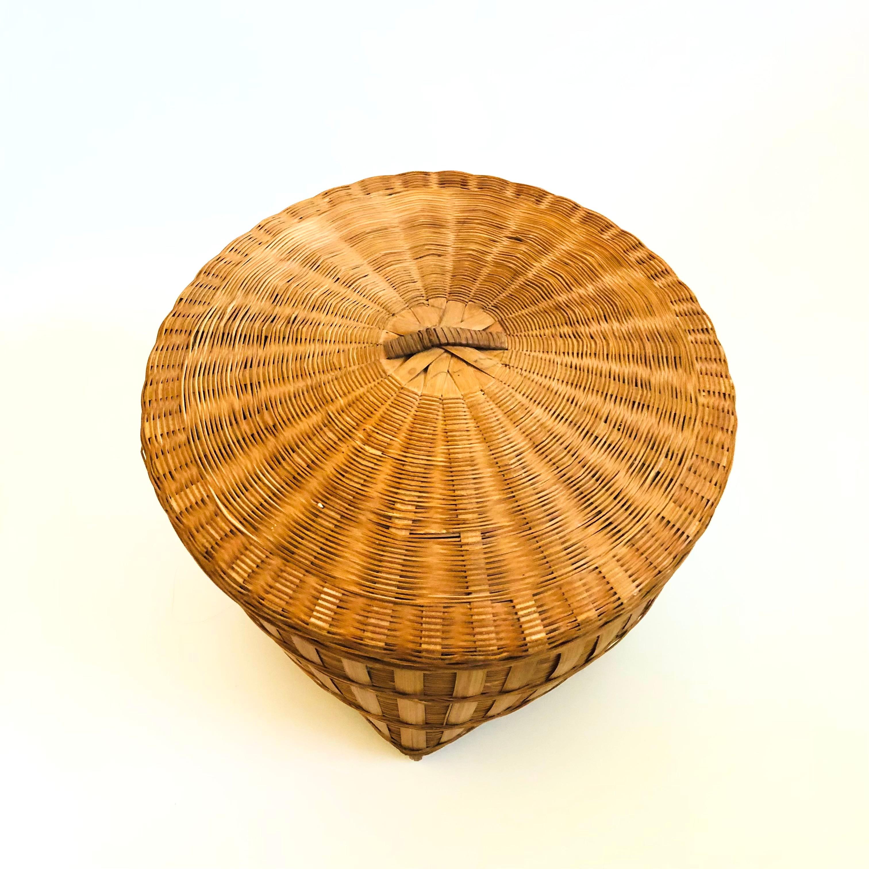 Una cesta vintage de mimbre con tapa y detalles de bambú.

