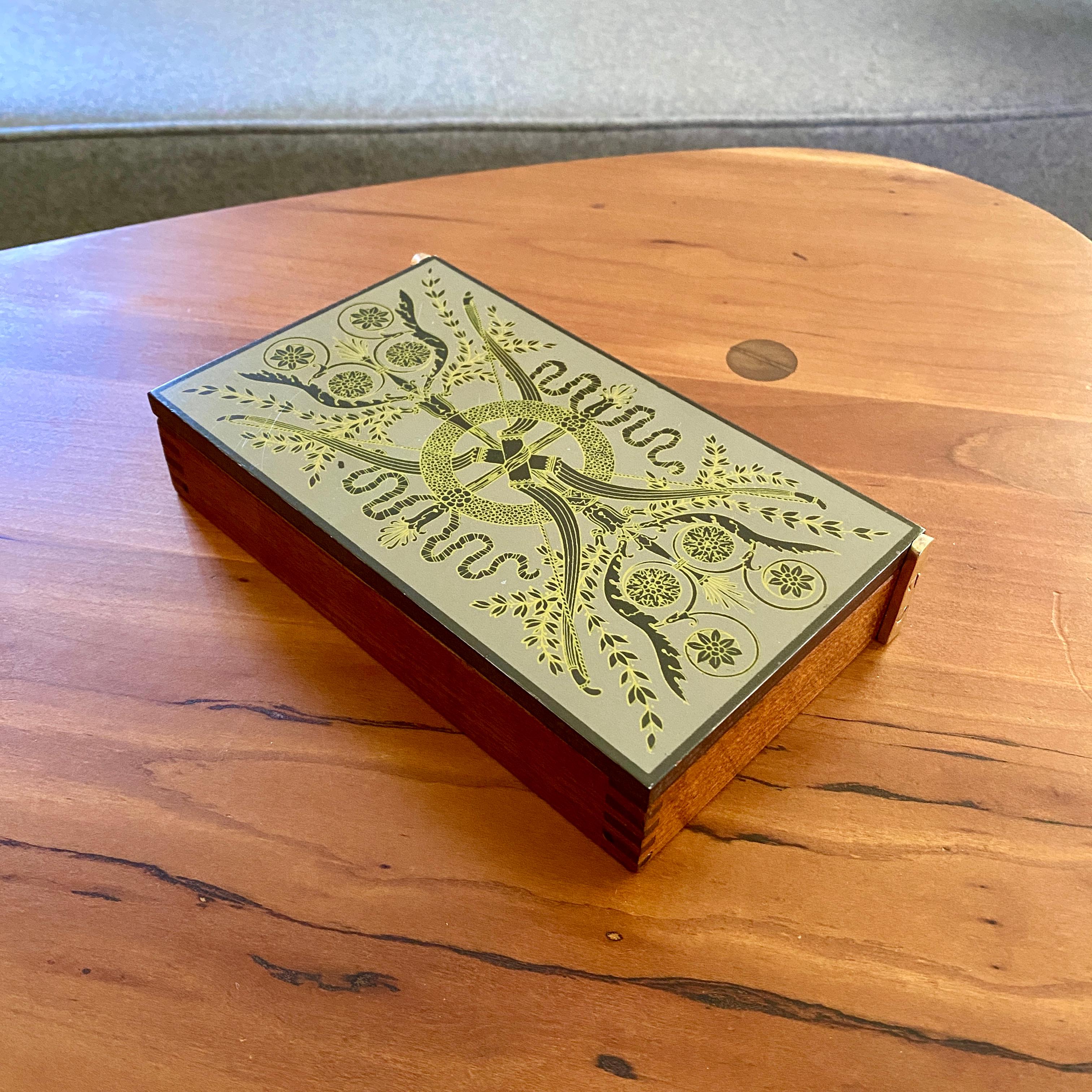 A vintage box with a brass hinged lid. The box was designed by Piero Fornasetti in the 1950s / 1960s. The box is composed of what appears to be a mahogany dovetailed wooden box, brass side hinges and with what looks to be a wood top with laminated
