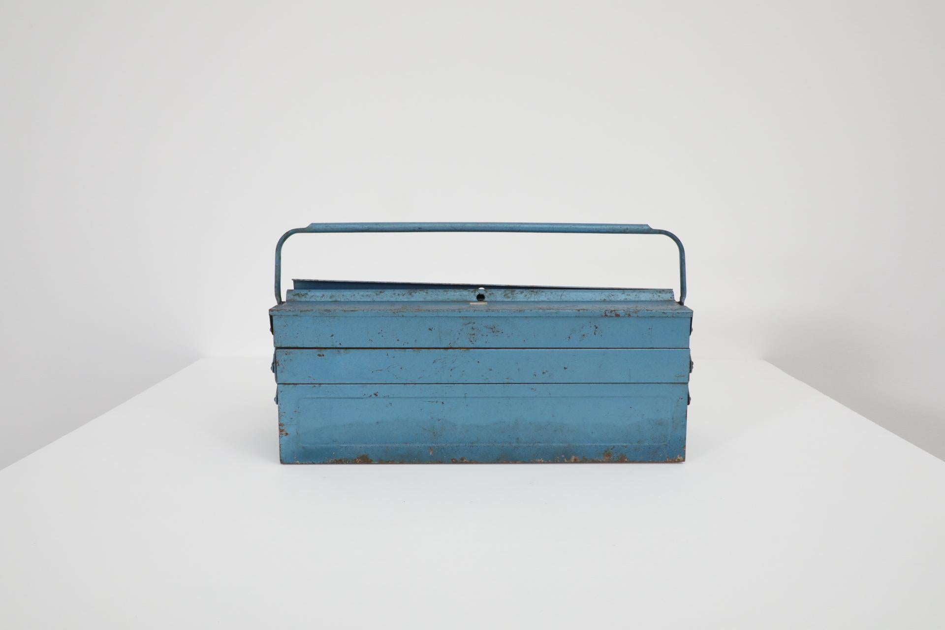 Vintage light blue metal tool box with handle and stacking trays. In original condition with visible wear, including enameled loss, discoloration and scratches. Wear is consistent with its age and use. 