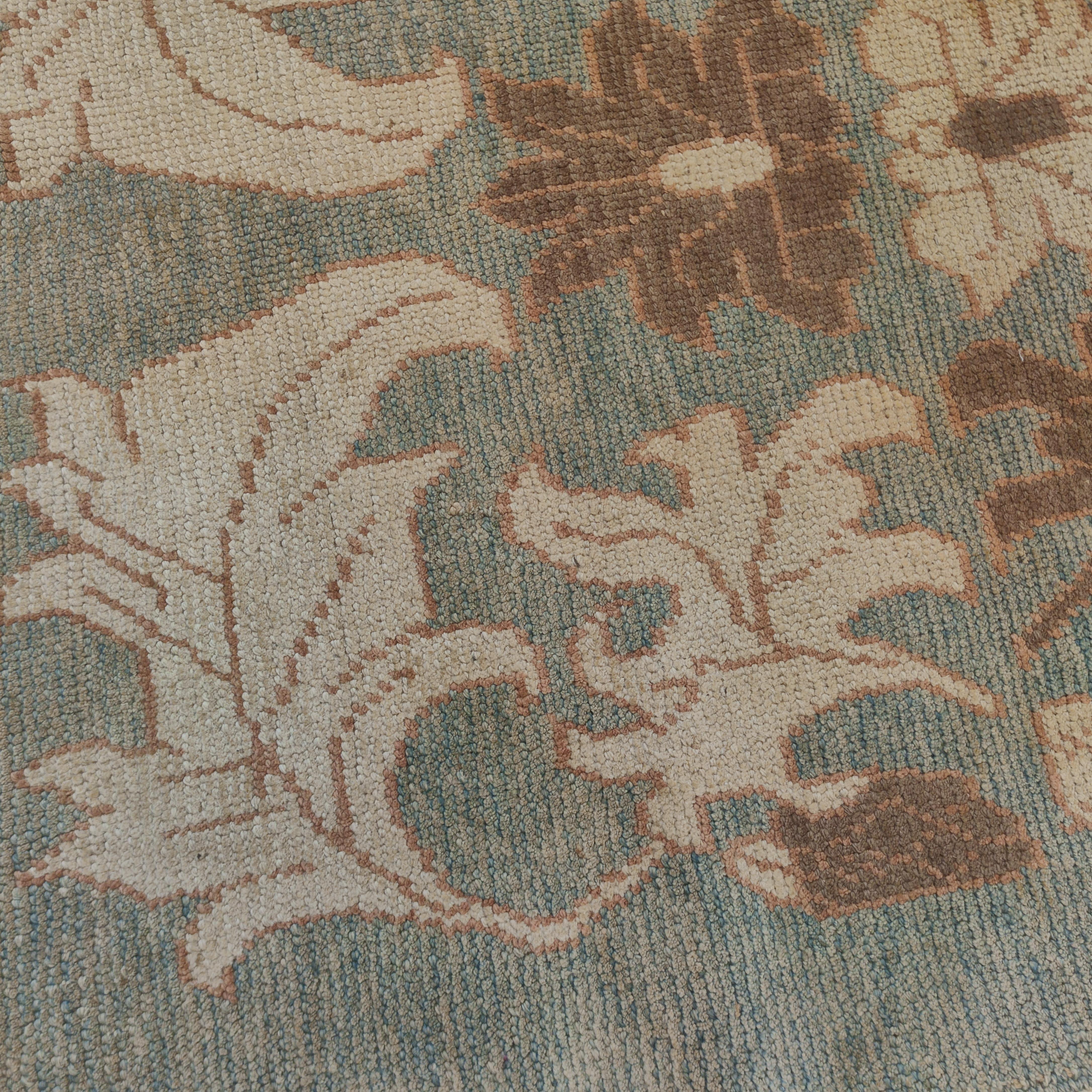 Ce tapis Oushak très raffiné se distingue par un magnifique fond bleu aqua, embelli par un motif surdimensionné composé d'une grande palmette centrale flanquée d'un réseau de feuilles finement dessinées en ivoire et brun clair. Les motifs de ce type
