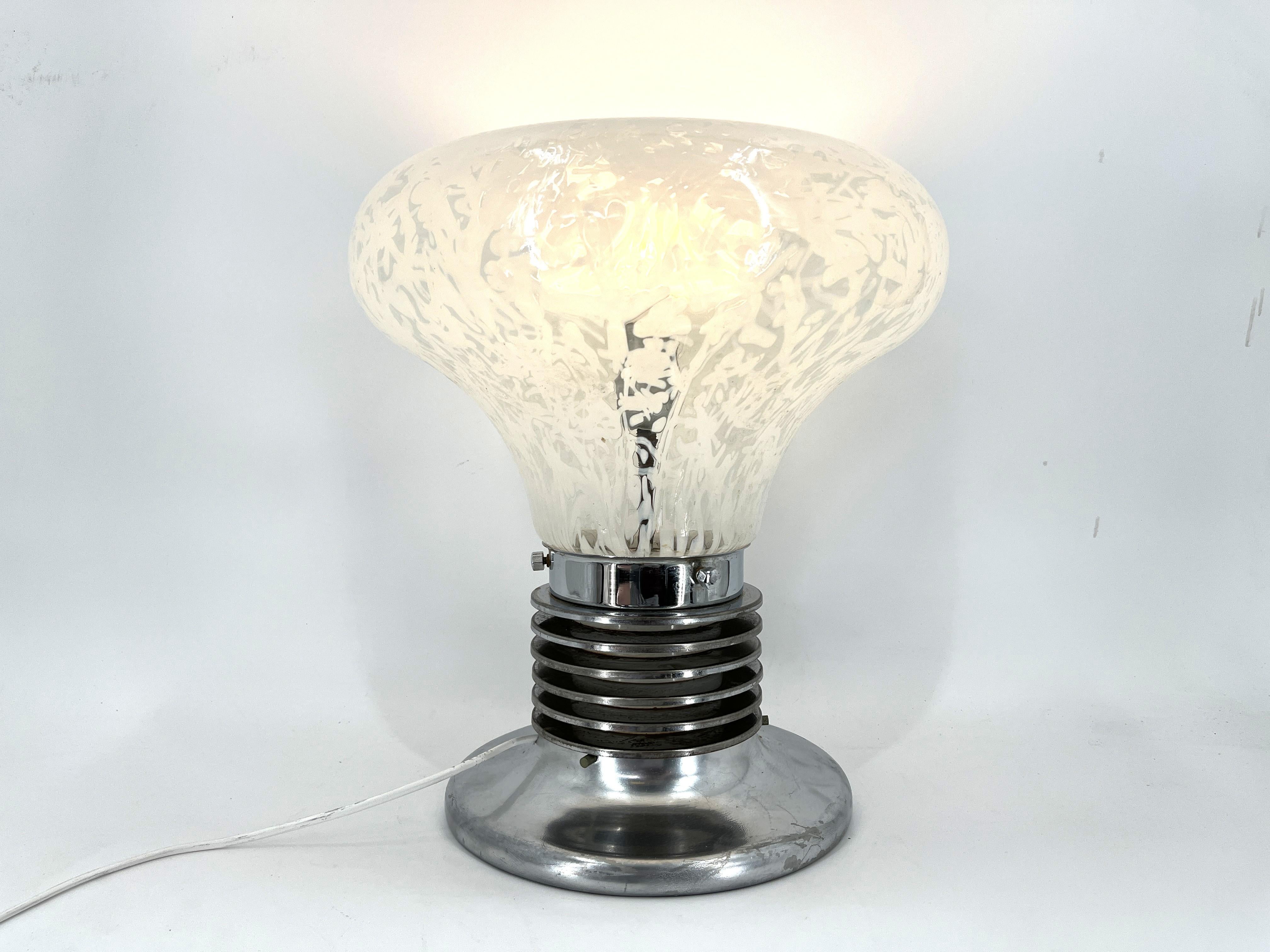 Mid century table lamp attributed to Carlo Nason for Mazzega with a murano glass lamp shade and a chromed metal b ase designed to be looking like a light bulb.

Beautiful mid century lamp which emits a soft dim light.

Good condition, tested and