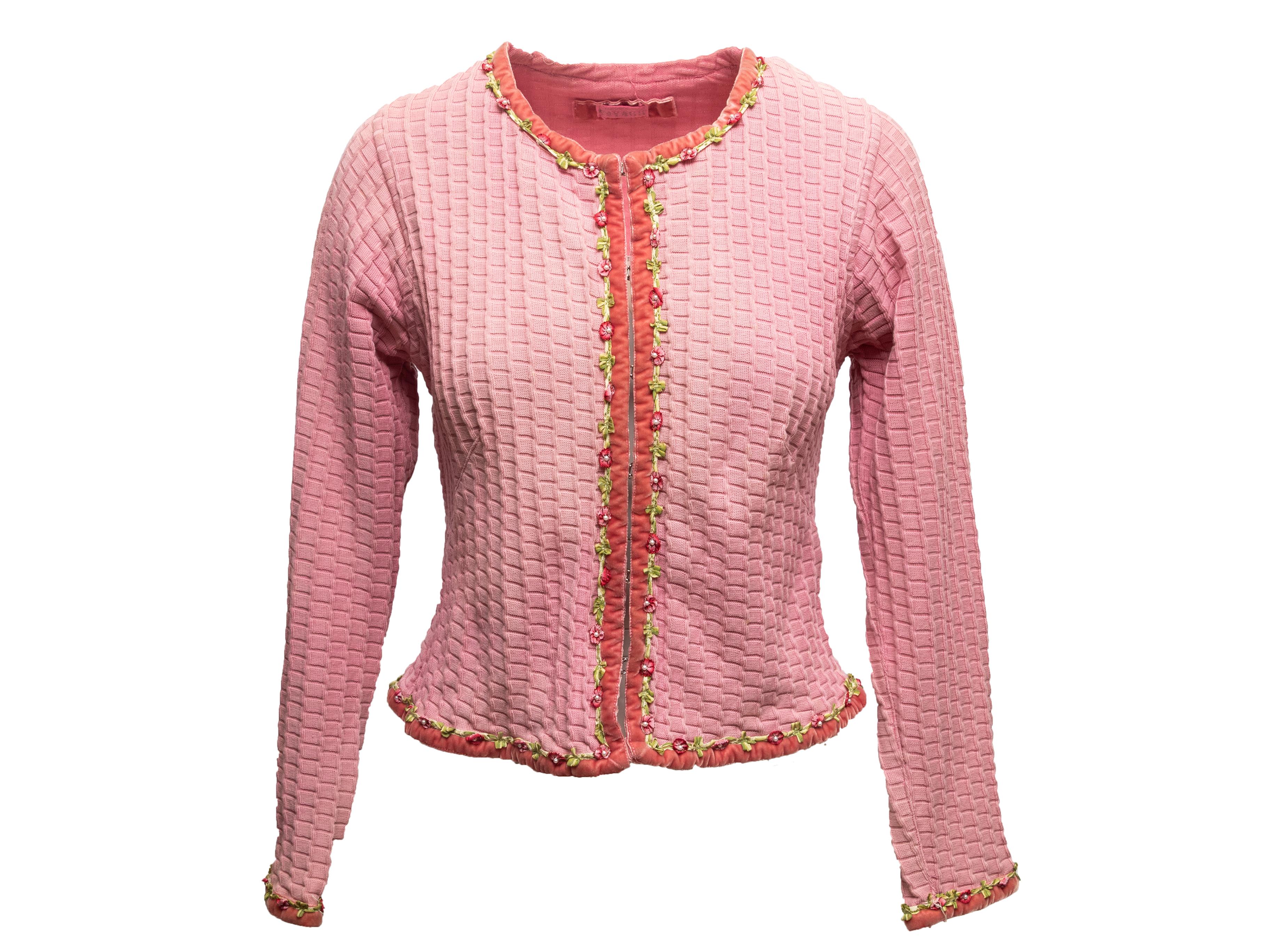 Hellrosa Strickjacke aus strukturierter Baumwolle von Voyage. Zierlicher Blumen- und Samtbesatz an allen Seiten. Rundhalsausschnitt. Haken- und Ösenverschlüsse vorne. 32