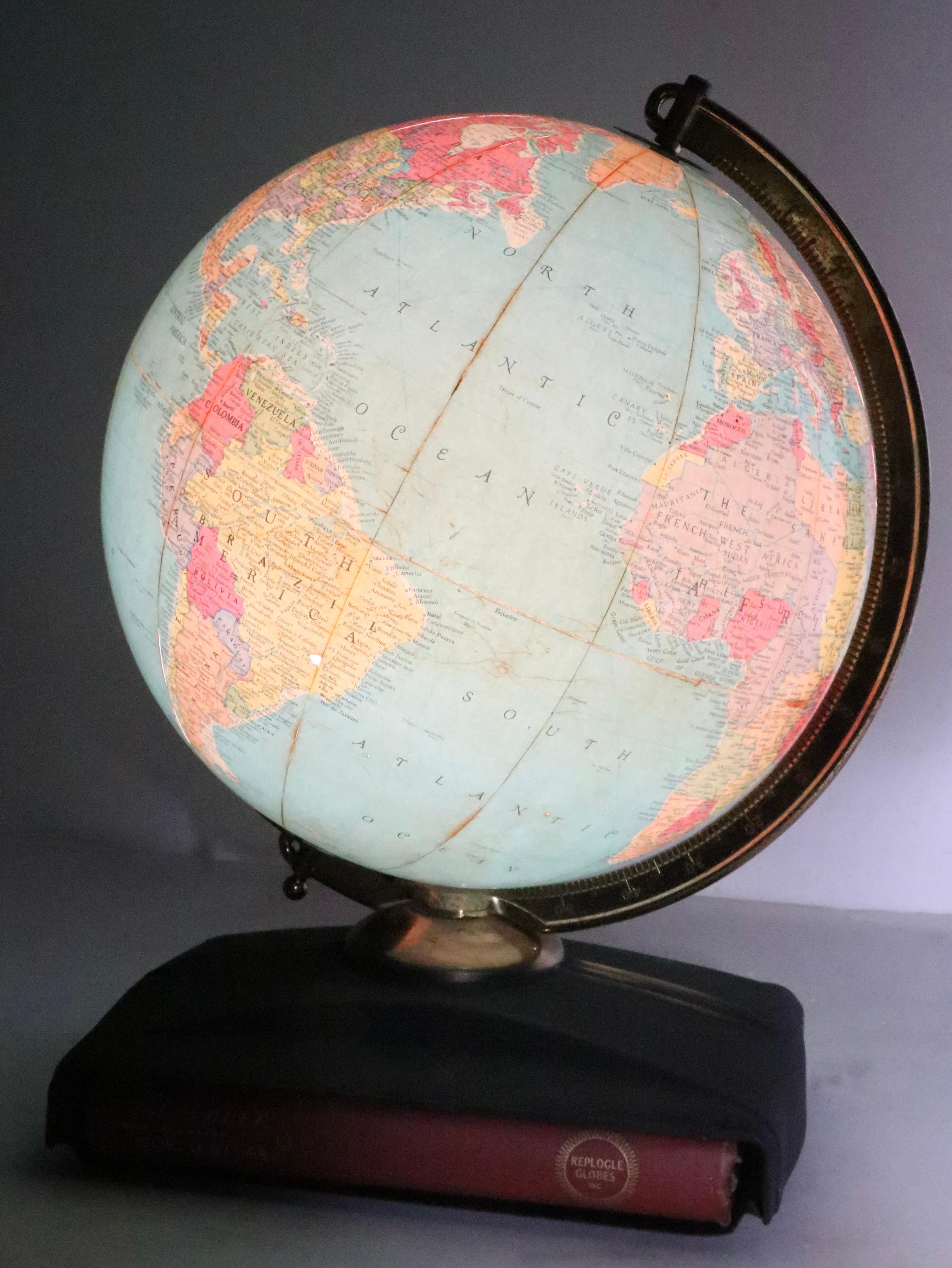 Grande Replogle Globes d'epoca, prodotto a Chicago, circa fine 1950/inizio 1960. Il globo si illumina, oltre a ruotare sul suo asse. Il mappamondo è montato su un supporto metallico stilizzato, che ospita l'atlante originale, oltre a varie mappe, un