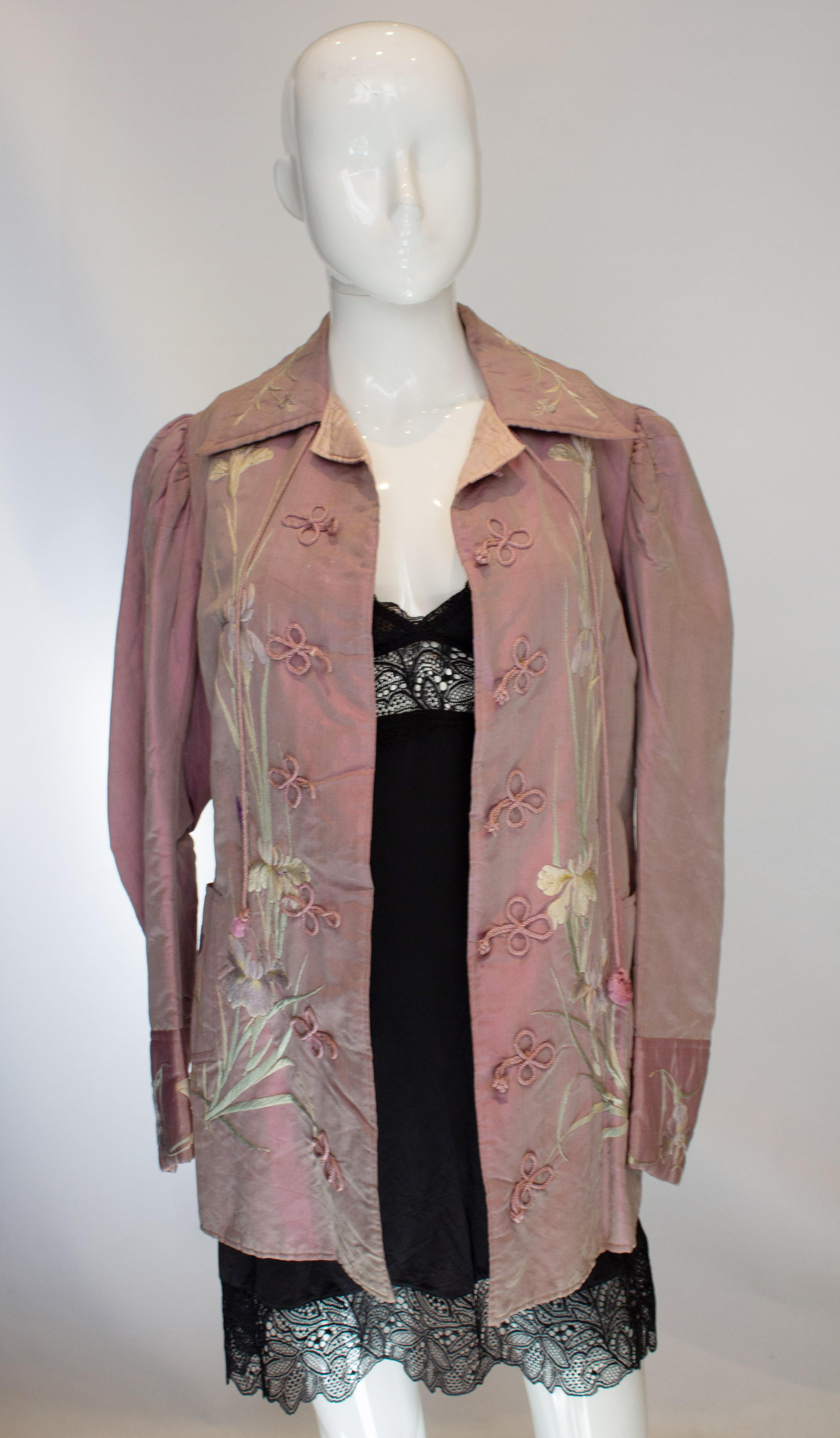 A pretty vintage silk jacket in a soft lilac colour with embroidery detail. The jacket has a quilted lining, with embroidery on the front and pockets. It has a slit at the back, tie at the kneck,  and gathering on the shoulders. 
Bust 35'', length