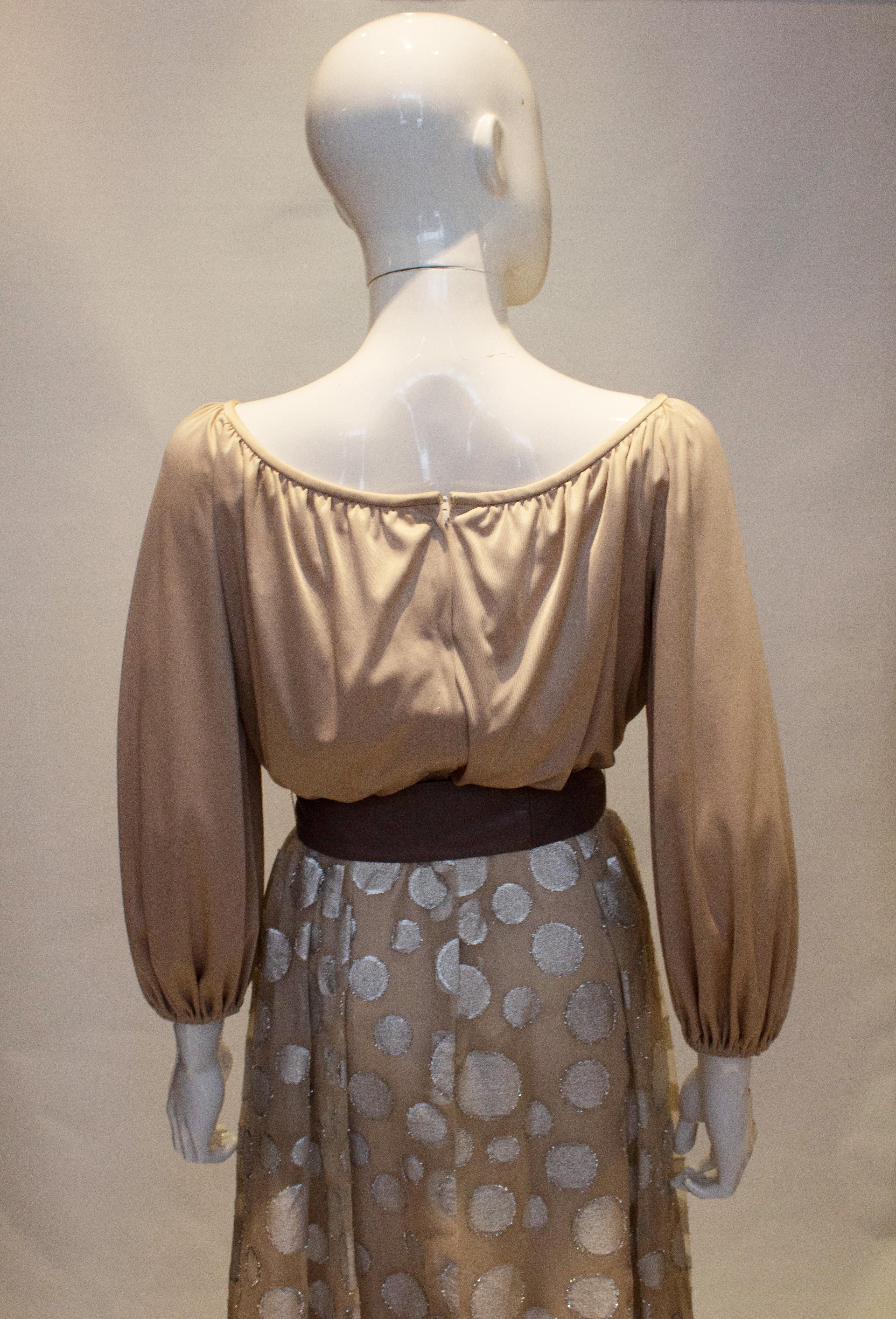 A great dress for the party season from Lilli Diamond of California..  The dress is in a soft grey/silver colour with a tie at the neck and elastic at the wrists. The skirt has decorative silver circles  and a full underskirt.  Measurements Bust up