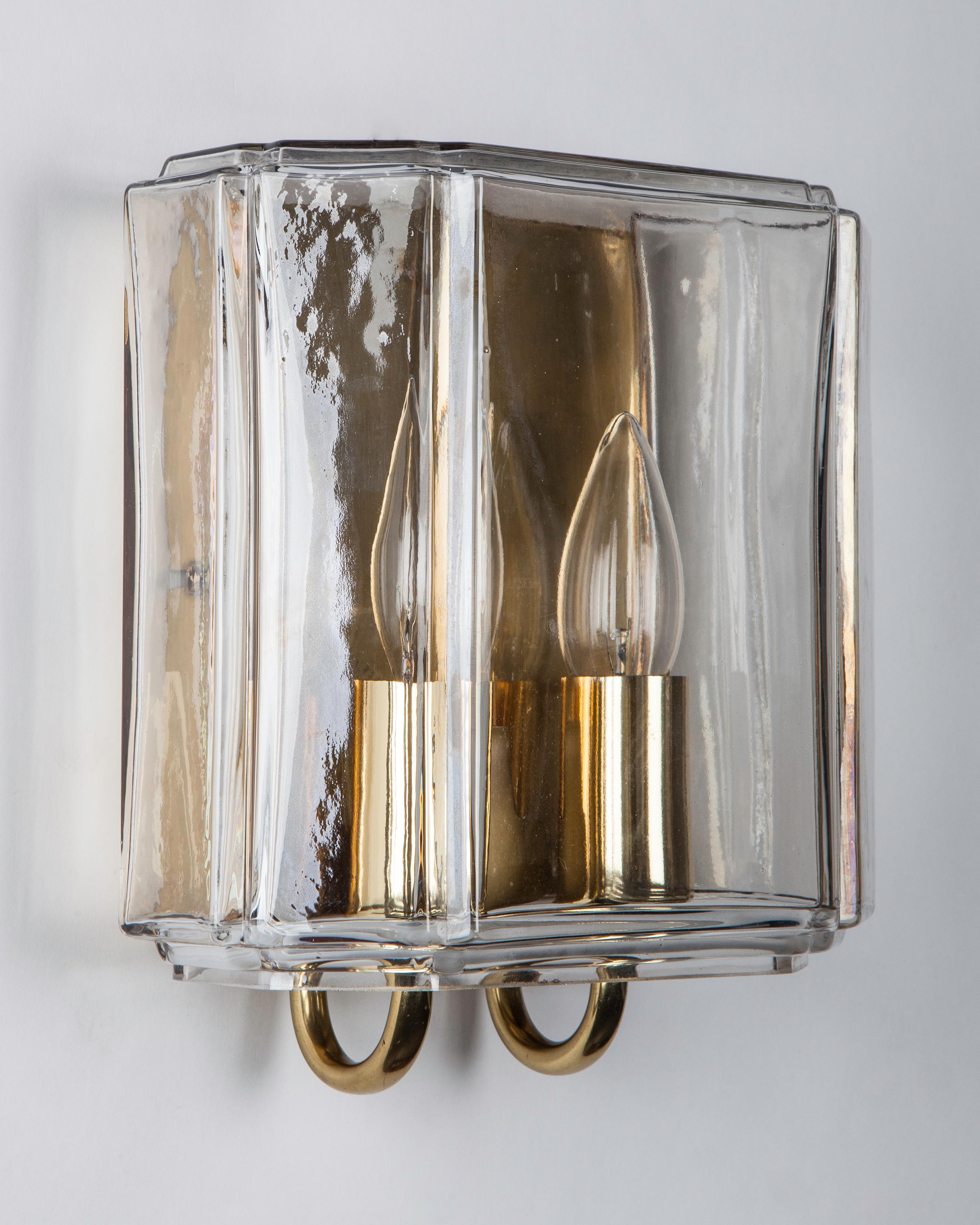 AIS3102
A pair of vintage double light sconces, each having simple aged polished brass metalwork with two arms surrounded by an unusual faceted glass lens. Attributed to the German maker Glashütte Limburg, circa 1960.

Dimensions:
Overall: 9-1/2