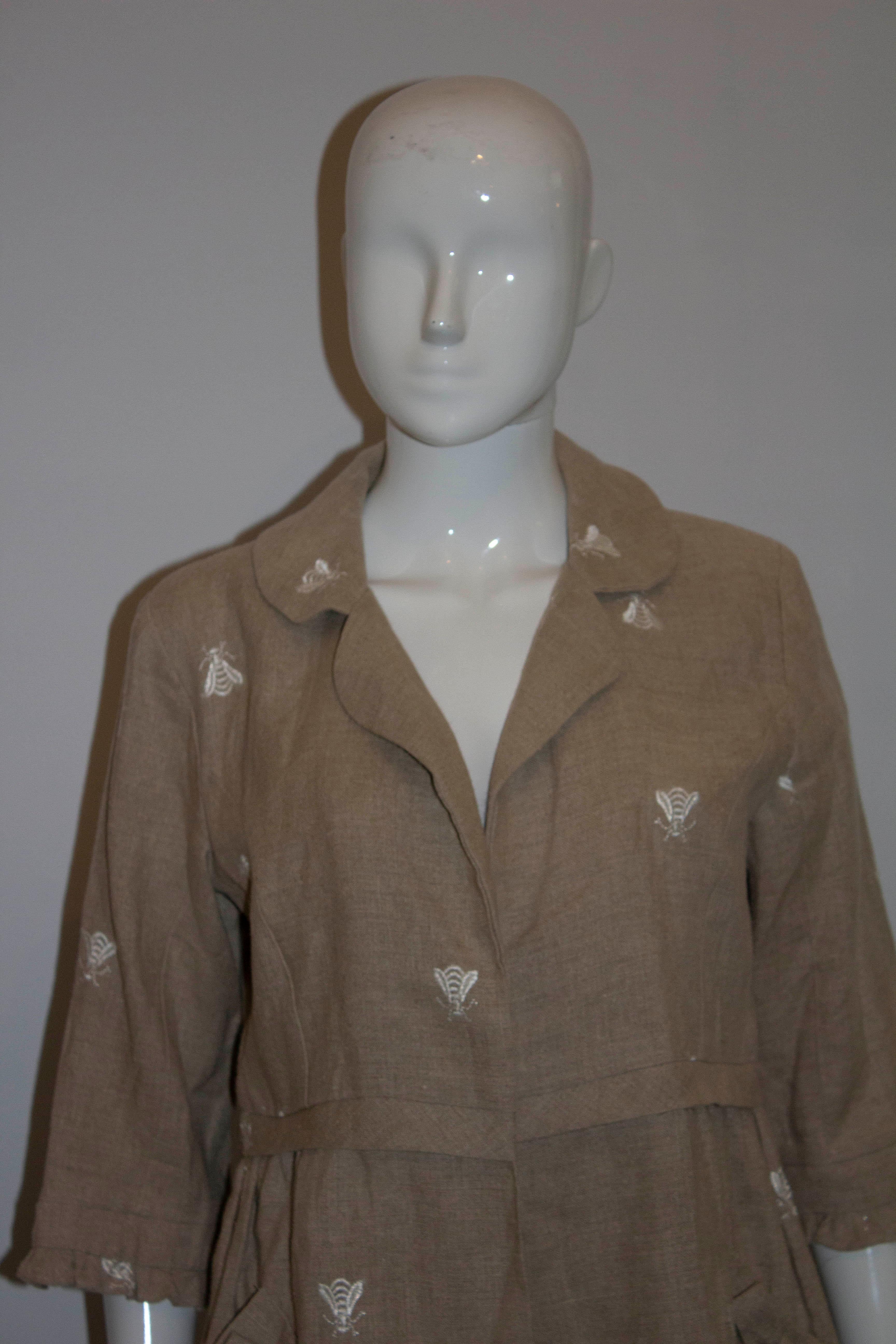 A pretty linen coat  in an attractive biscuit colour. The coat has elbow length sleaves with frill detail , a pocket on either side , gathering at the waist  and a cut away collar. It has white embroidery detail of insects.

Measurements: Bust up to