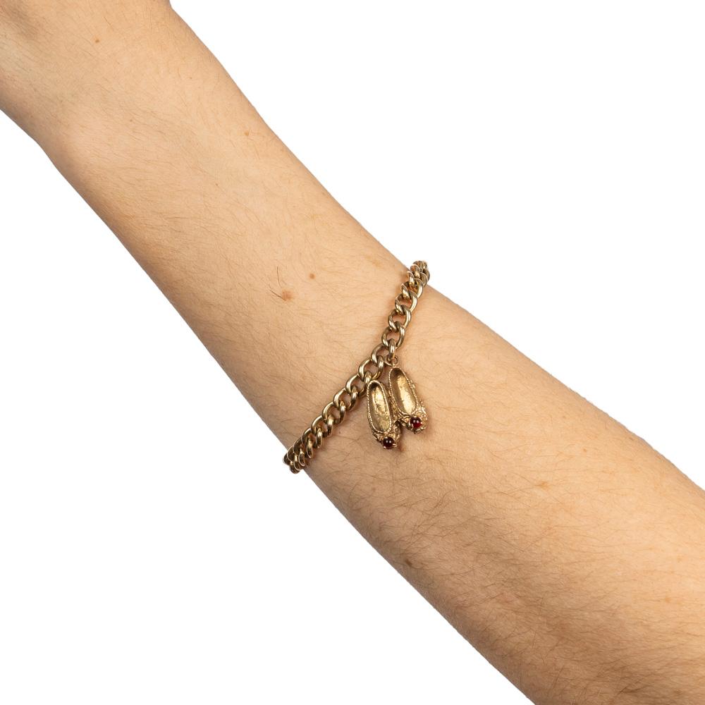 Ce magnifique bracelet à breloques vintage au design typique rappelle l'époque où de tels bracelets faisaient fureur, avec des maillons robustes en forme de cygne se terminant par une paire de ballerines ou de pantoufles en or jaune 10k, chacune