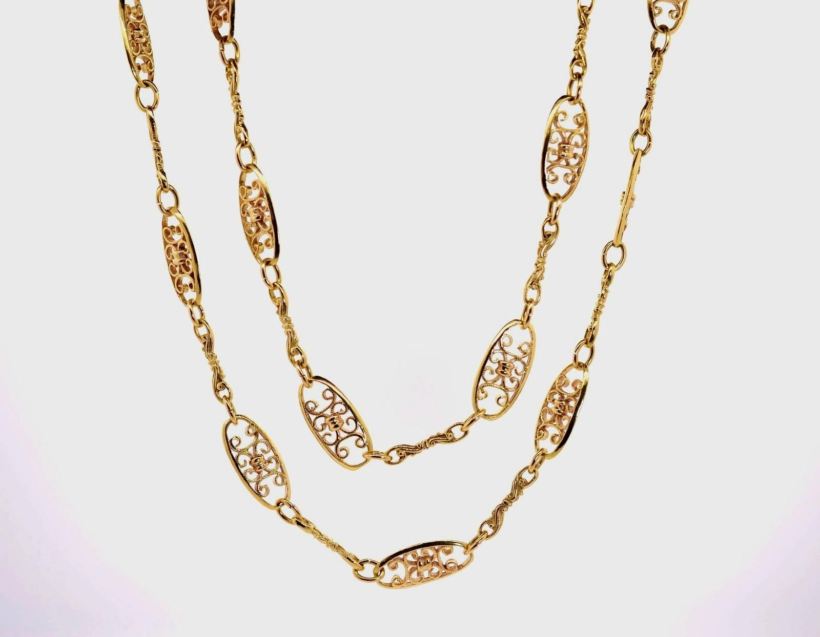 Hand crafted in the 1960s, this lovely chain of open wire links is created in 14KT yellow gold.  The numerous large oval links are embellished with inner swirl designs and are joined with baroque-like bar links giving the chain a 36 inch long