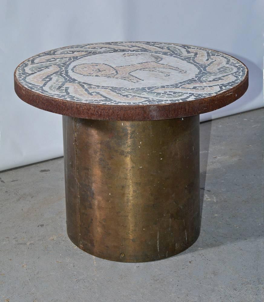 The vintage coffee, side or end table is composed of a brass drum base and a round mosaic tile top. The standing lion is encircled by a classical rope pattern. The tile colors are charcoal grey, grey green, tan, soft pink and white. The mosaic