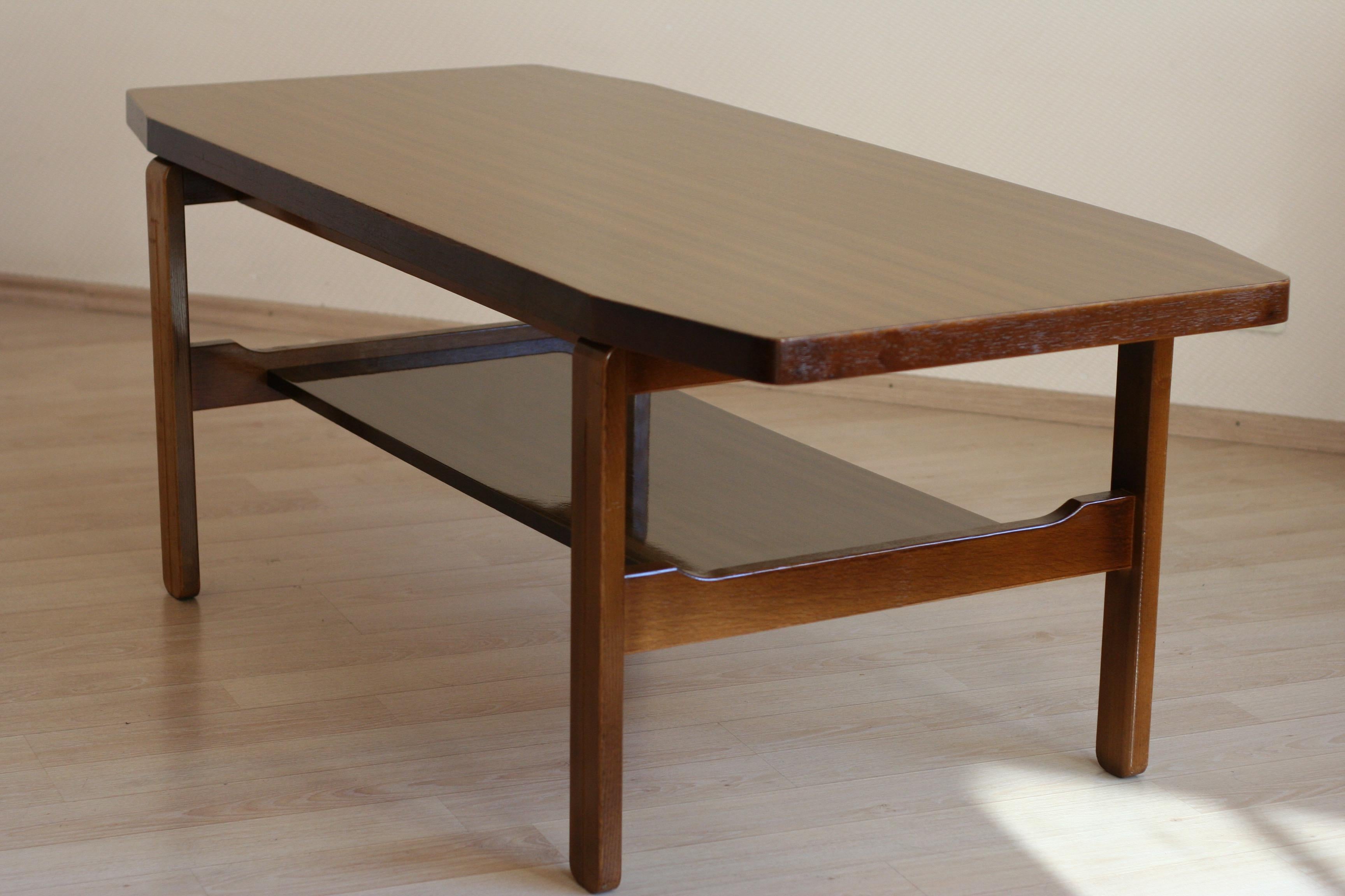 This coffee table features oakwood base and high gloss veneered hardwood desk. The desk is really heavy, so the table is very stabile. Due to uncommon hexagon form and no acute angles this coffee table looks very light in the room despite its quite