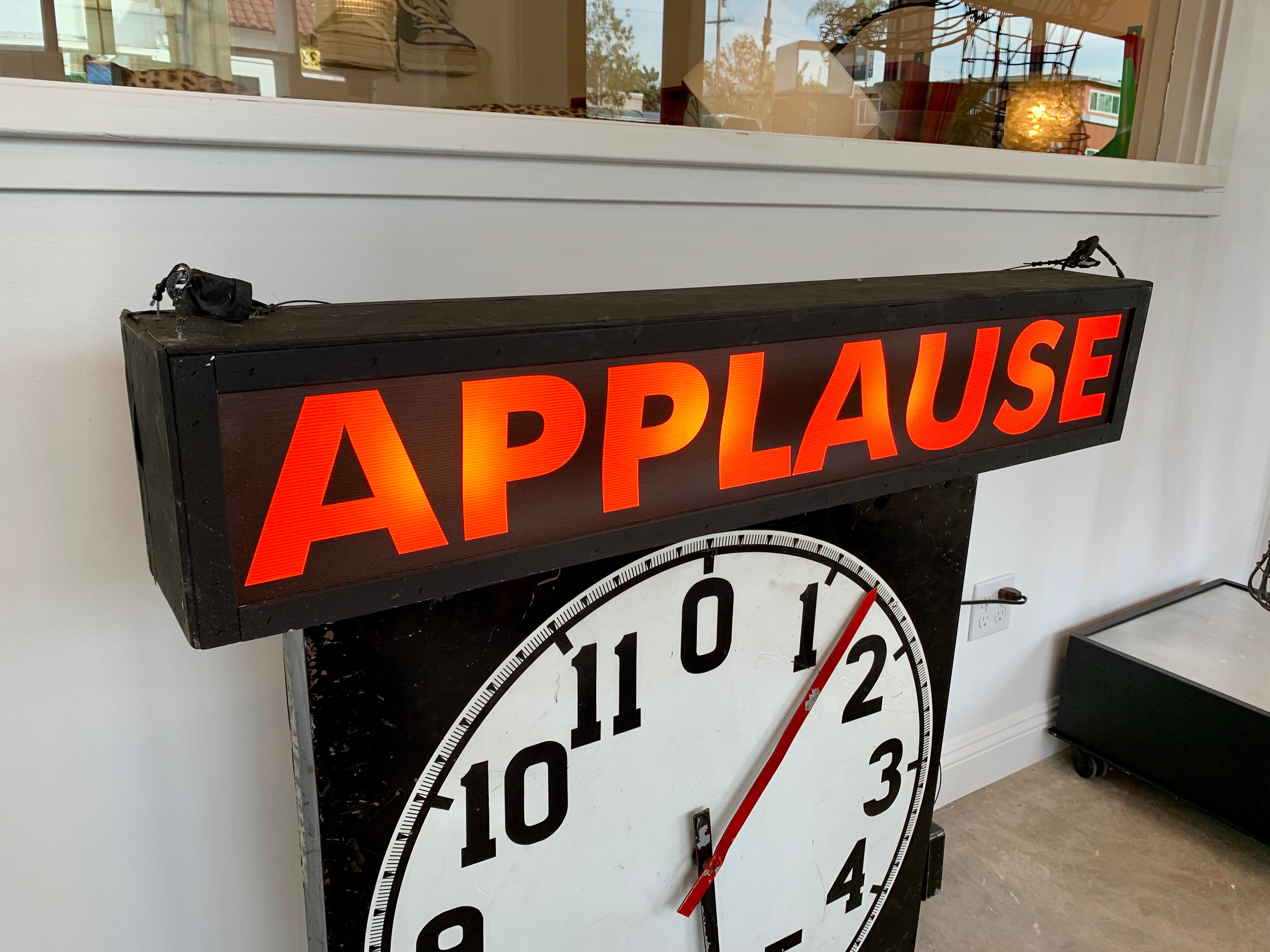Interesting illuminated APPLAUSE sign. Taken out of an old TV studio. Black painted wood with a light weight fabric making up the bright orange letters. Newly rewired. Cool piece of wall art.