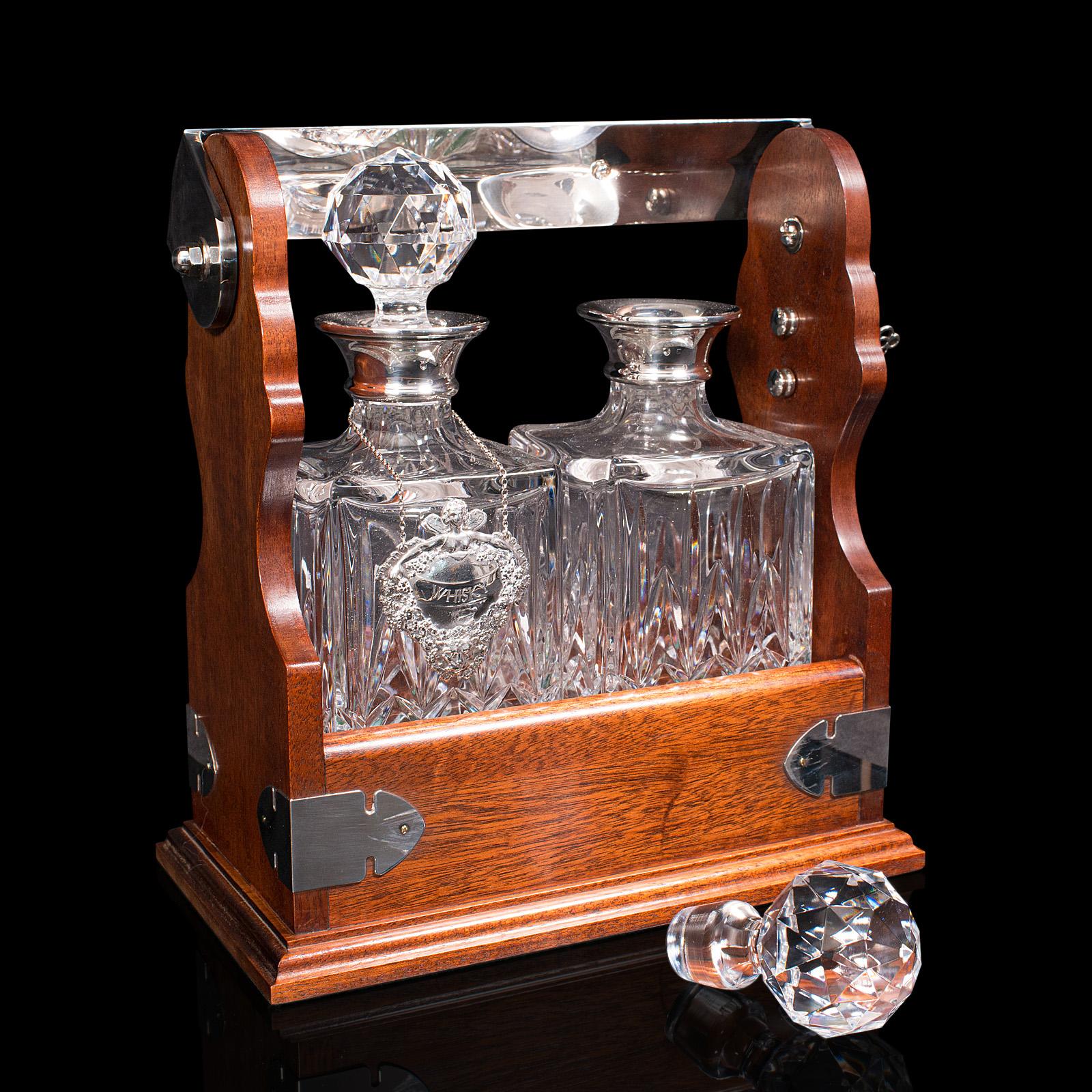 This is a vintage locking spirit Tantalus. An English, mahogany two decanter stand with hallmarked silver label and collar, dating to the late 20th century, circa 1990.

Useful and attractive tantalus with fine decorative appeal
Displays a