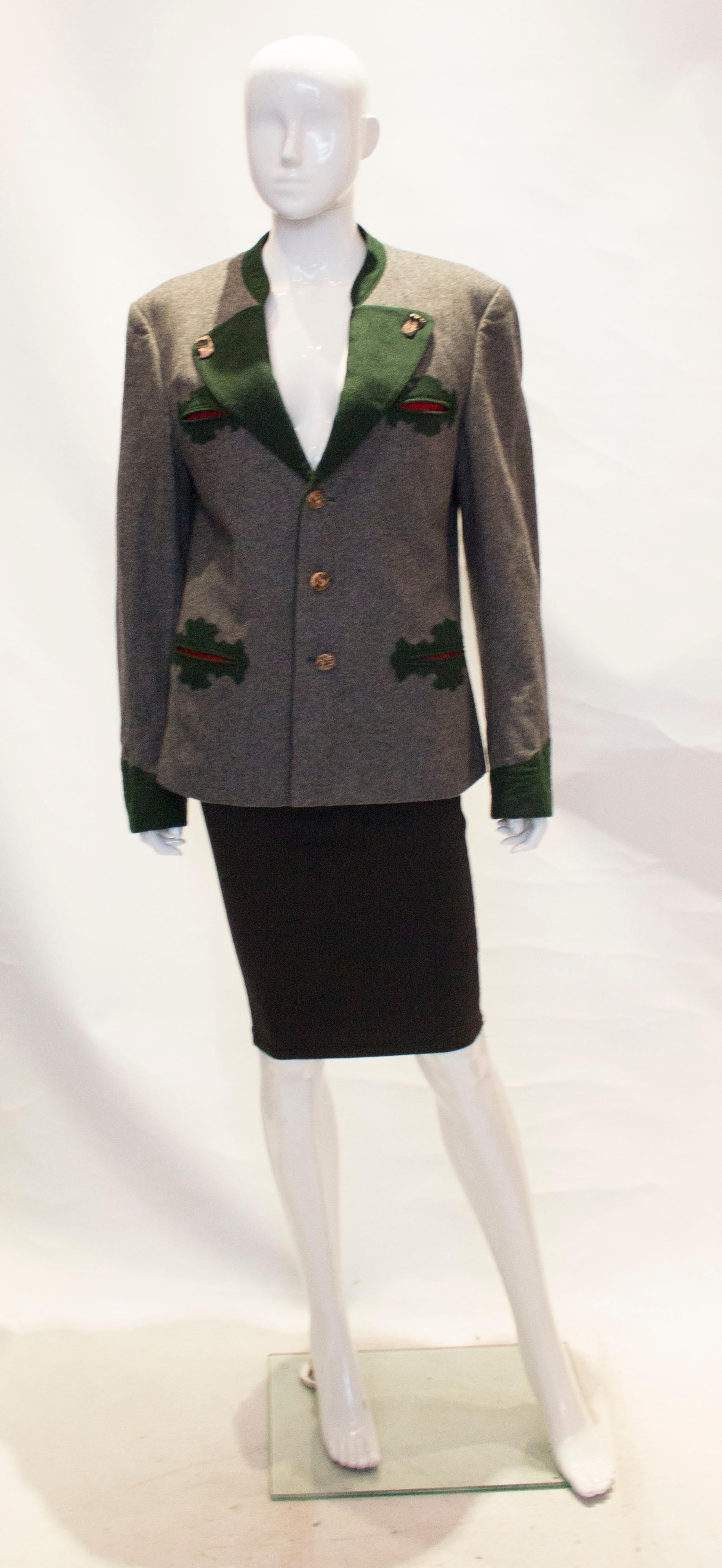 This vintage Loden jacket is suitable for a small guy or a girl. It is grey with green detail and  horn buttons, and has a breast pocket and two pockets at hip leval. It has a stand up and cut away collar with two flaps at the back, and is fully