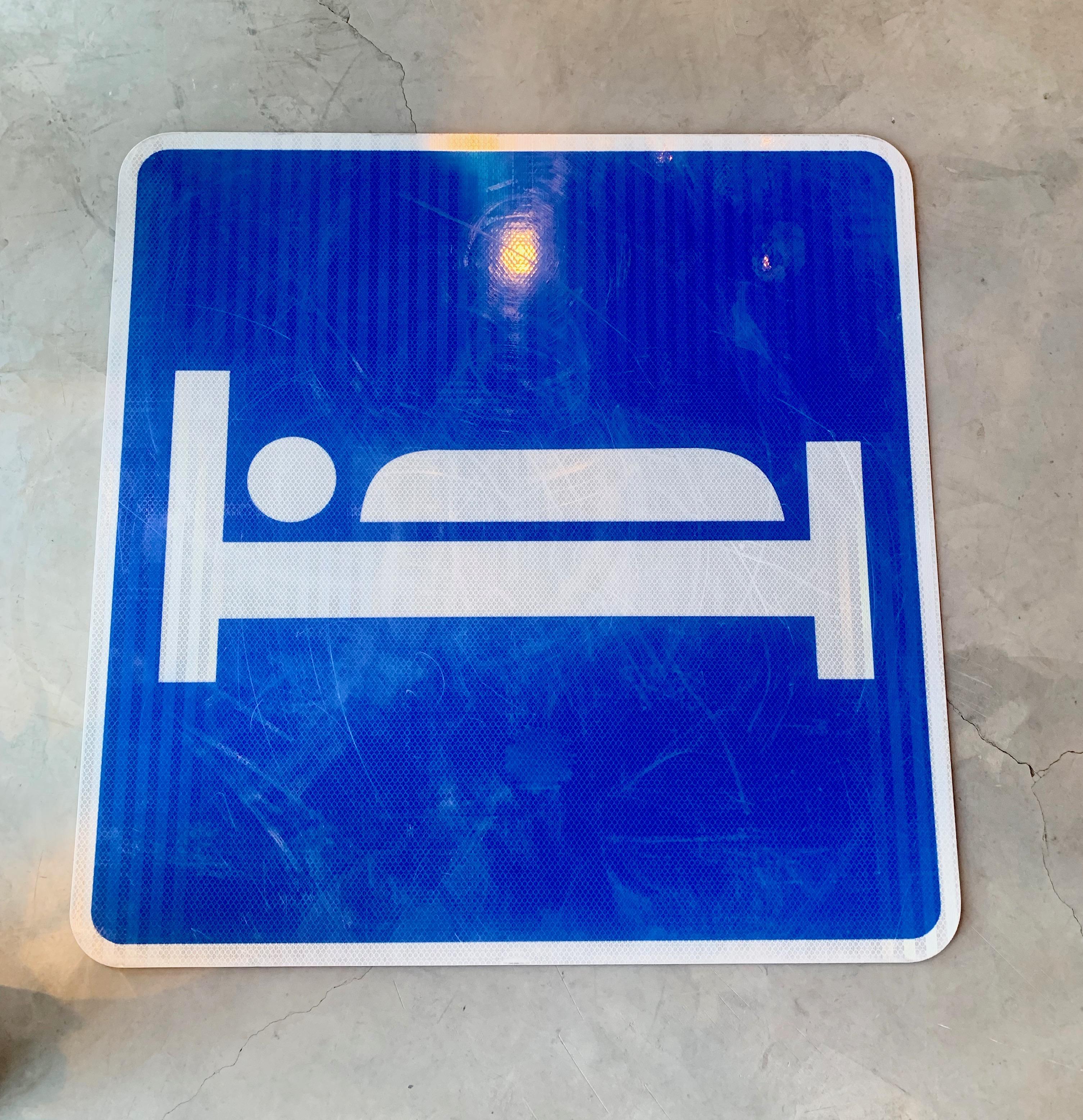 Cooles Vintage-Autobahnschild aus kobaltblauem, reflektierendem Metall. Zeigt eine Person, die im Bett schläft. Das Schild diente dazu, Autofahrer zu Hotels/Motels an der Straße zu leiten. Großes Format mit 30