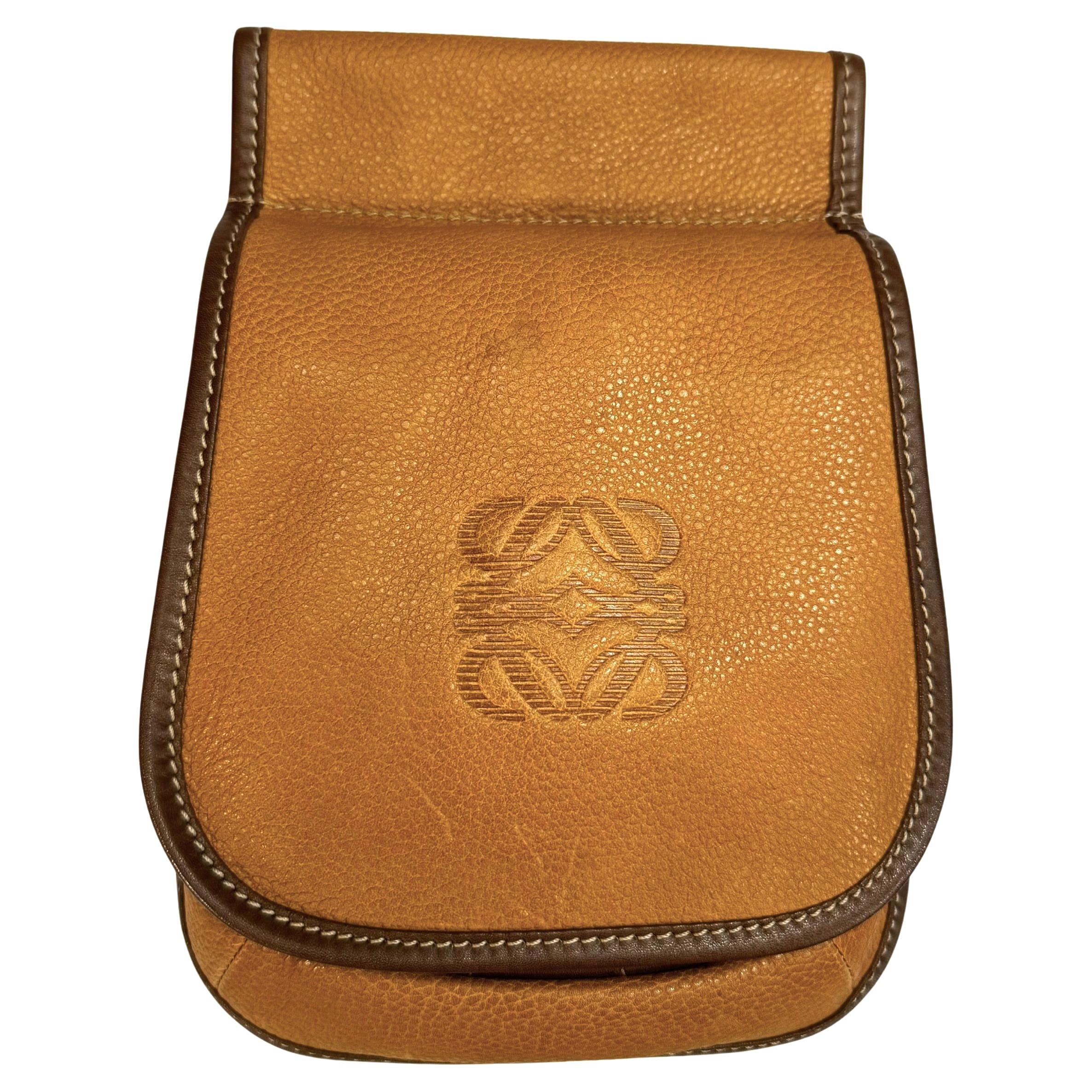 Diese LOEWE Anagram Gürteltasche im Vintage-Stil ist aus grob genarbtem Kalbsleder in Senfgelb gefertigt und mit glattem Kalbsleder in Braun abgesetzt. Die Frontklappe öffnet sich zu einem ungefütterten Innenraum aus Wildleder und Steckfächern aus