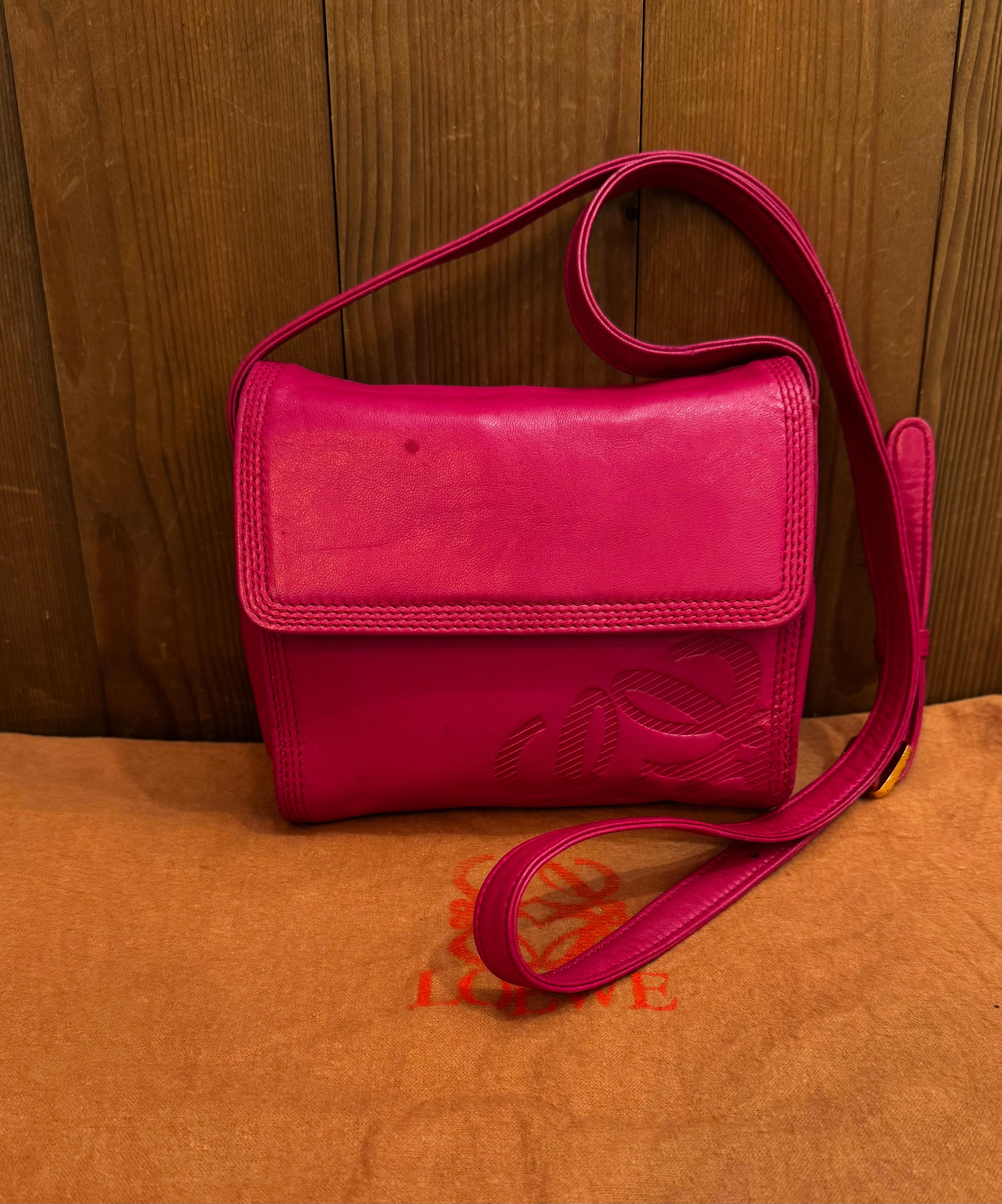 Ce mini sac crossbody vintage LOEWE Anagram à côtés souples est confectionné en cuir de veau souple de couleur rose. Le rabat avant à fermeture magnétique s'ouvre sur un intérieur enduit qui a été nettoyé par des professionnels, avec une pochette à