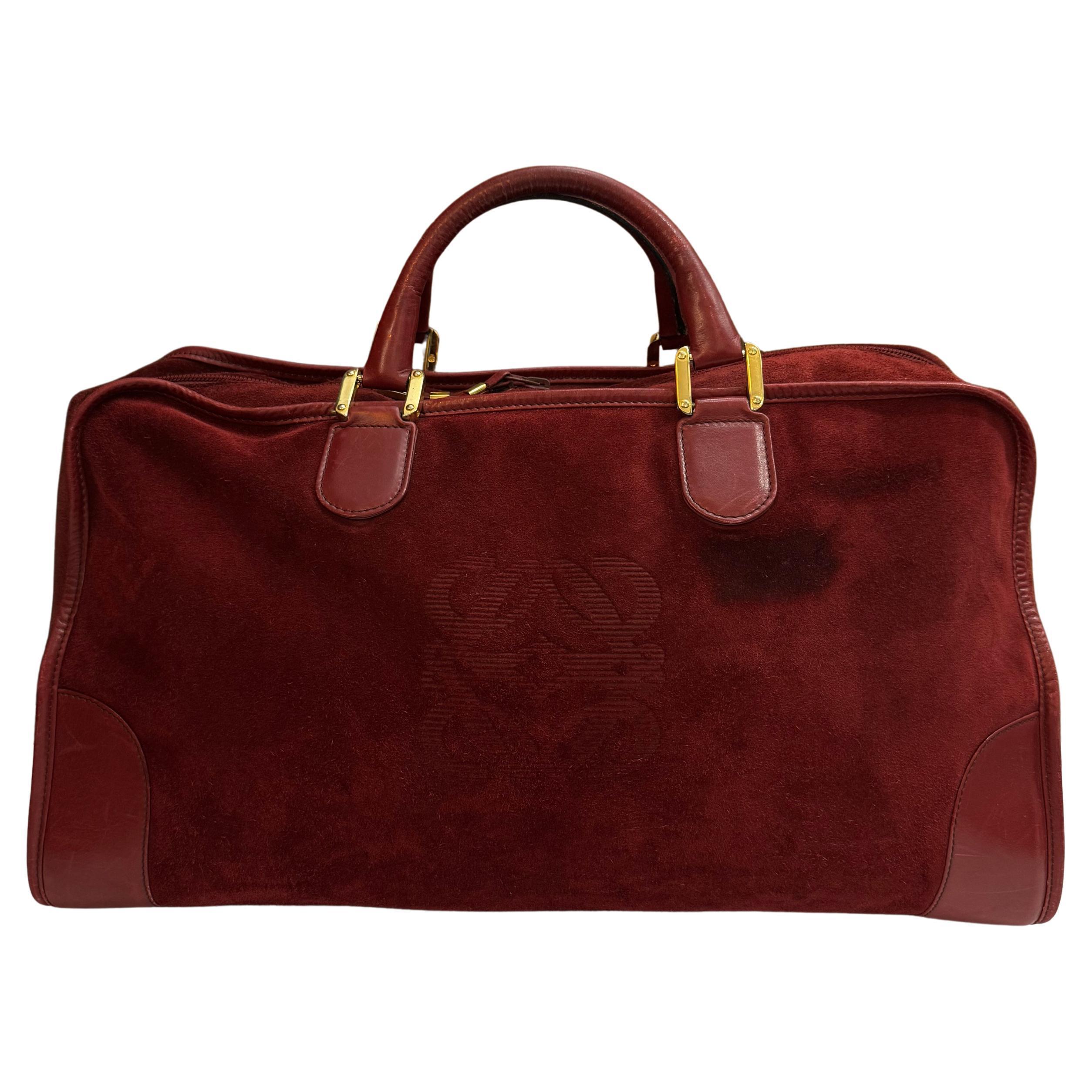 Diese Vintage LOEWE Anagram Amazona Boston Tasche ist aus Wildleder und glattem Kalbsleder in Burgunderrot gefertigt und mit goldfarbenen Beschlägen und gerollten Ledergriffen versehen. Der Reißverschluss an der Oberseite führt zu einem