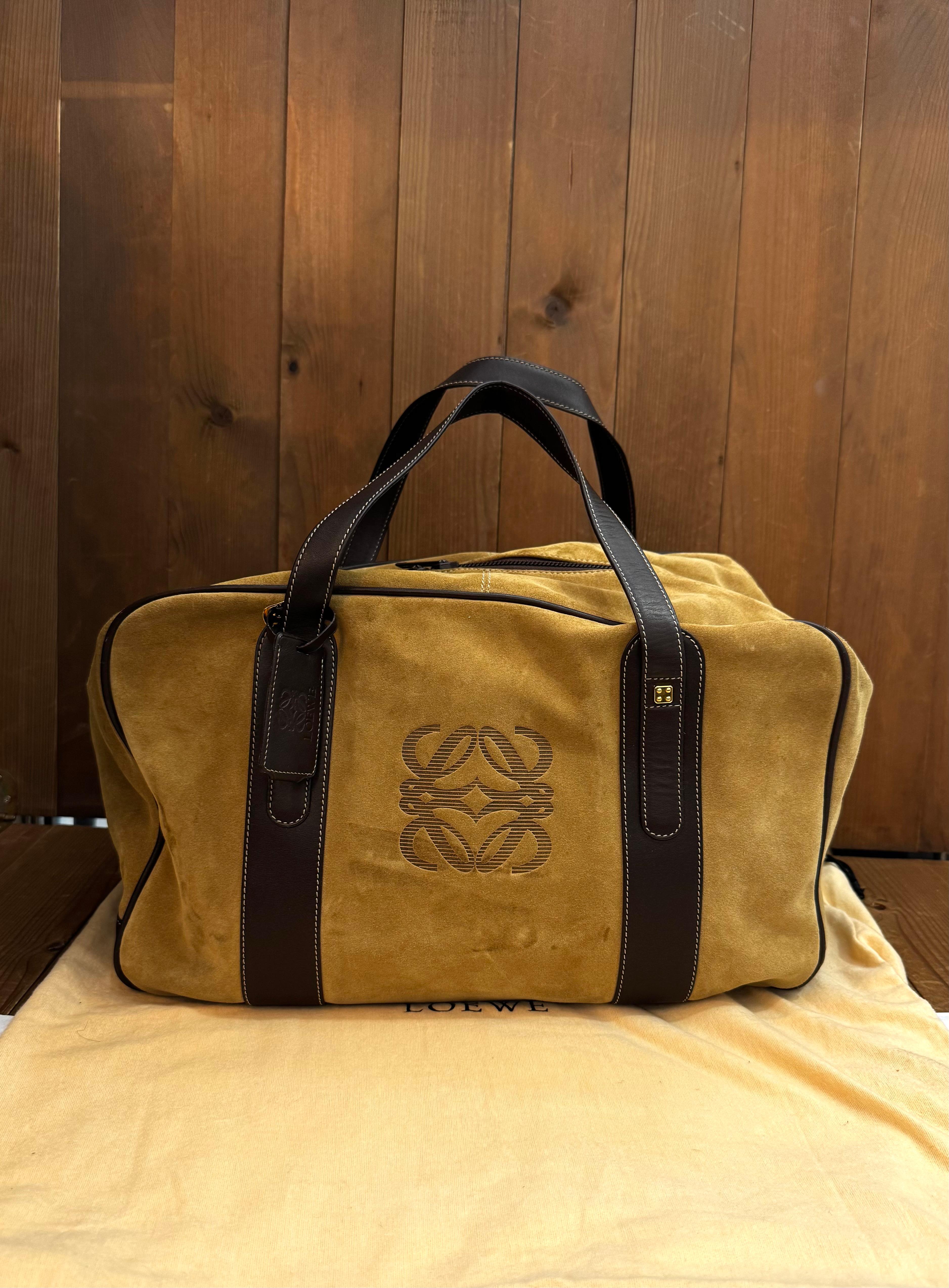 This vintage LOEWE Anagram boston bag is crafted of suede and smooth calfskin leather in brown featuring gold toned hardware. Double zipper closures open to an anagramed cotton fabric interior. The exterior of this Loewe also has a zippered pocket