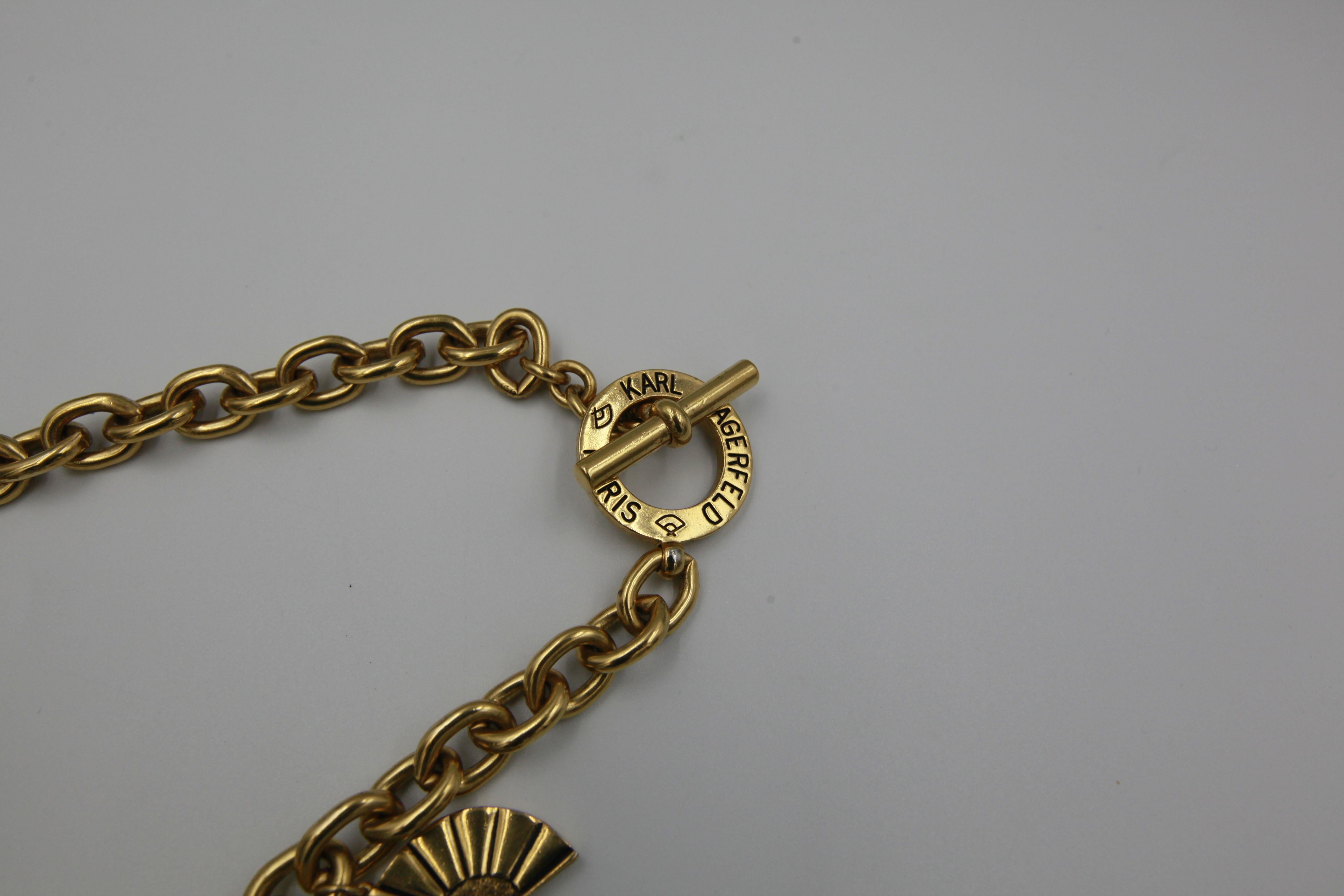 Vintage signature chain statement Karl Lagerfeld necklace in gold-tone metal featuring fan and Logo rings charms.
Signed. 
Period: 1990s
Chain length: 47 cm
Condition: Very Good. Minor scratches throughout metal.


........Additional information