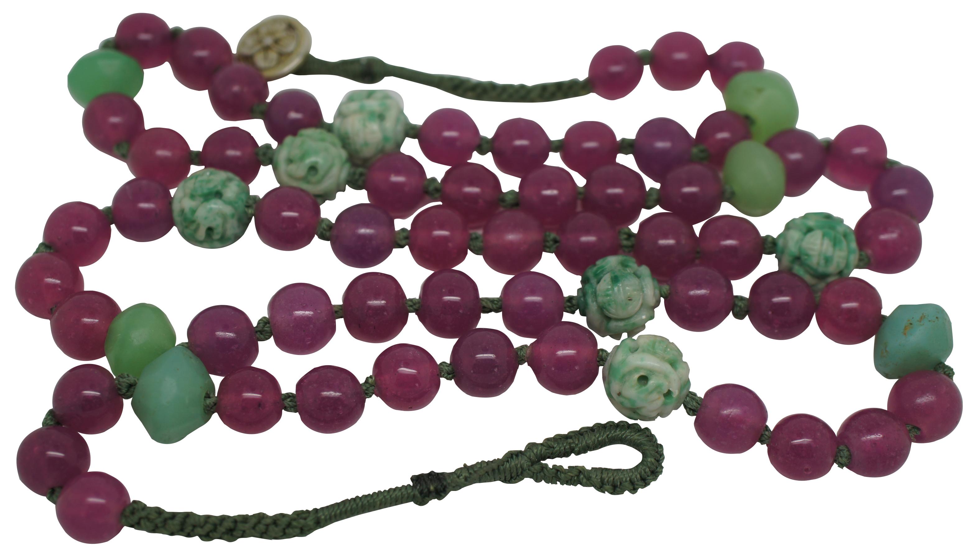 Vintage necklace of long alternating naturally irregular and carved Chinese dragon jade beads, and pink / magenta glass beads strung on a hand knotted cord. Measures: 40
