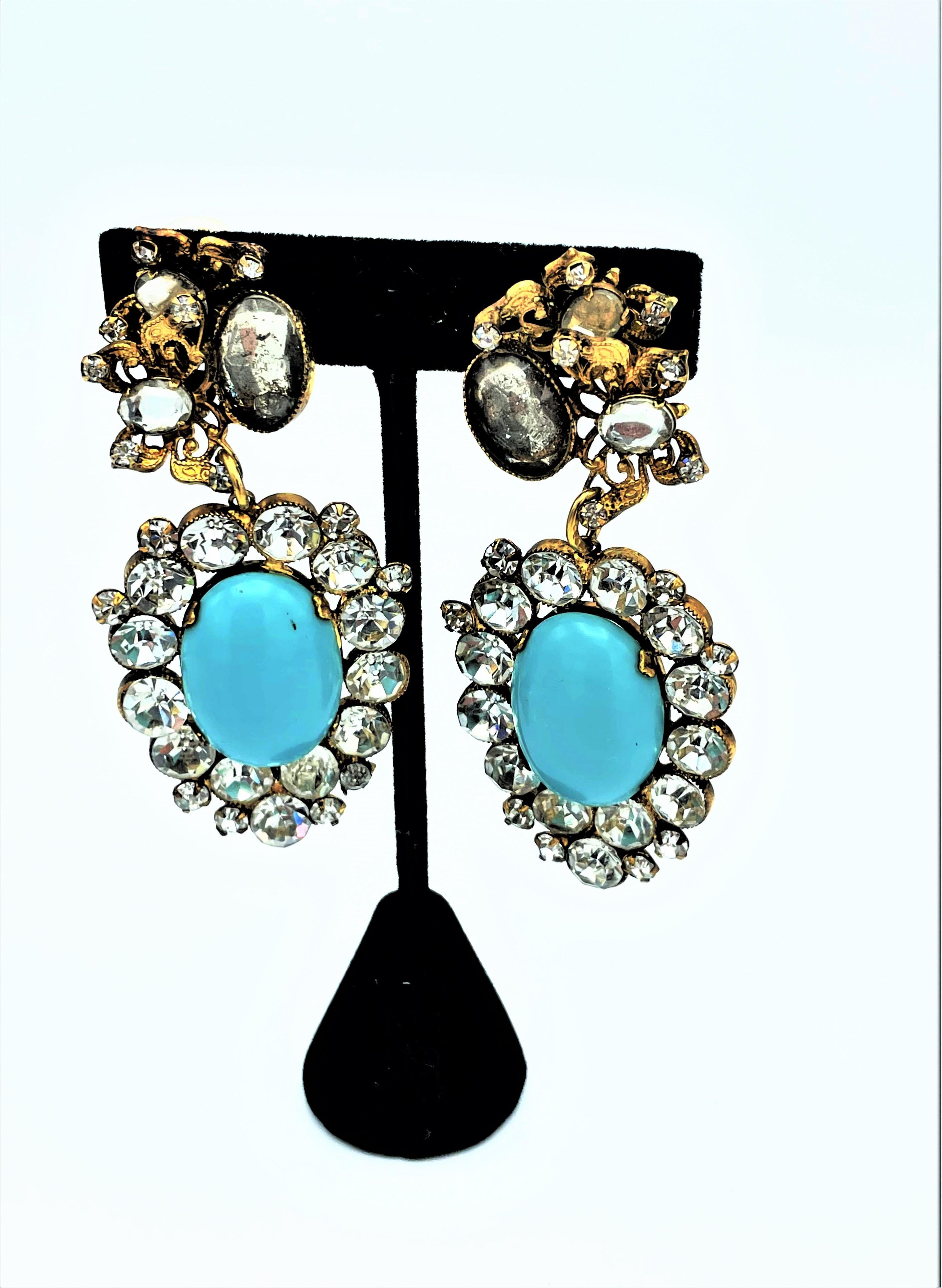 Great long ear clips by DeLilo from the early 1950's USA. Decorated with 2 butterflies on the upper part. Attached to it is a large oval with a turquoise glass stone surrounded by large cut rhinestones.
A very interesting and extremely decorative