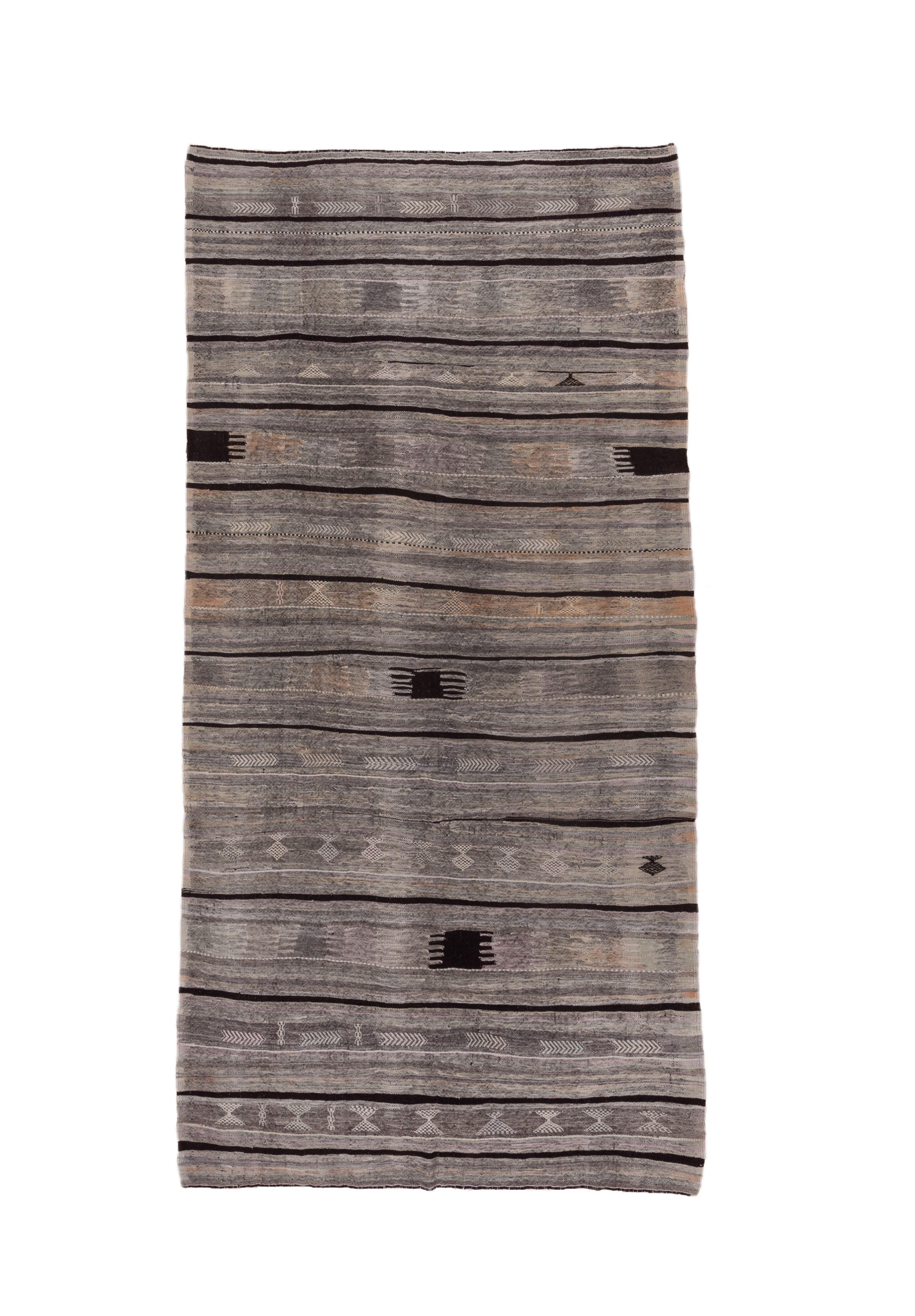 This single piece Anatolian village flatweave shows horizontal bands, some with dark brown accent sections, in simple geometric patterns, in shades of beige and tan. Chocolate brown narrow full or partial dividing lines. A few other dark brown