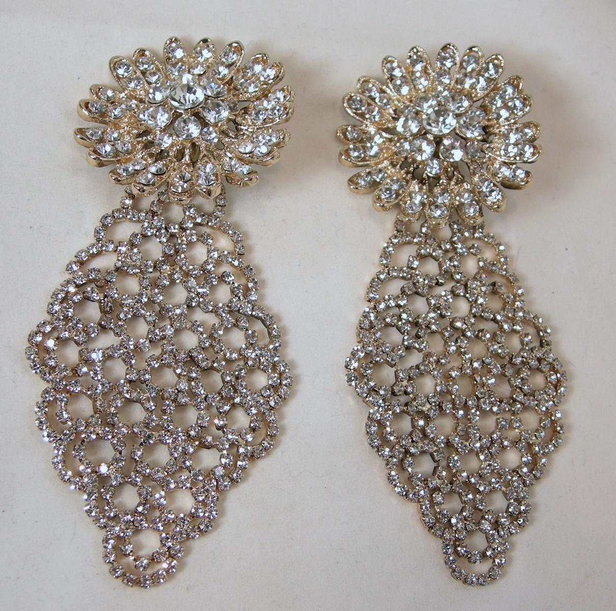 These long runway earrings are signed DeMario.  The top has a large 3-dimensional floral design with a long dangling drop.  The drop has brilliant, clear crystals in a gold tone setting.  In excellent condition, these clip earrings measure 4-3/4” x
