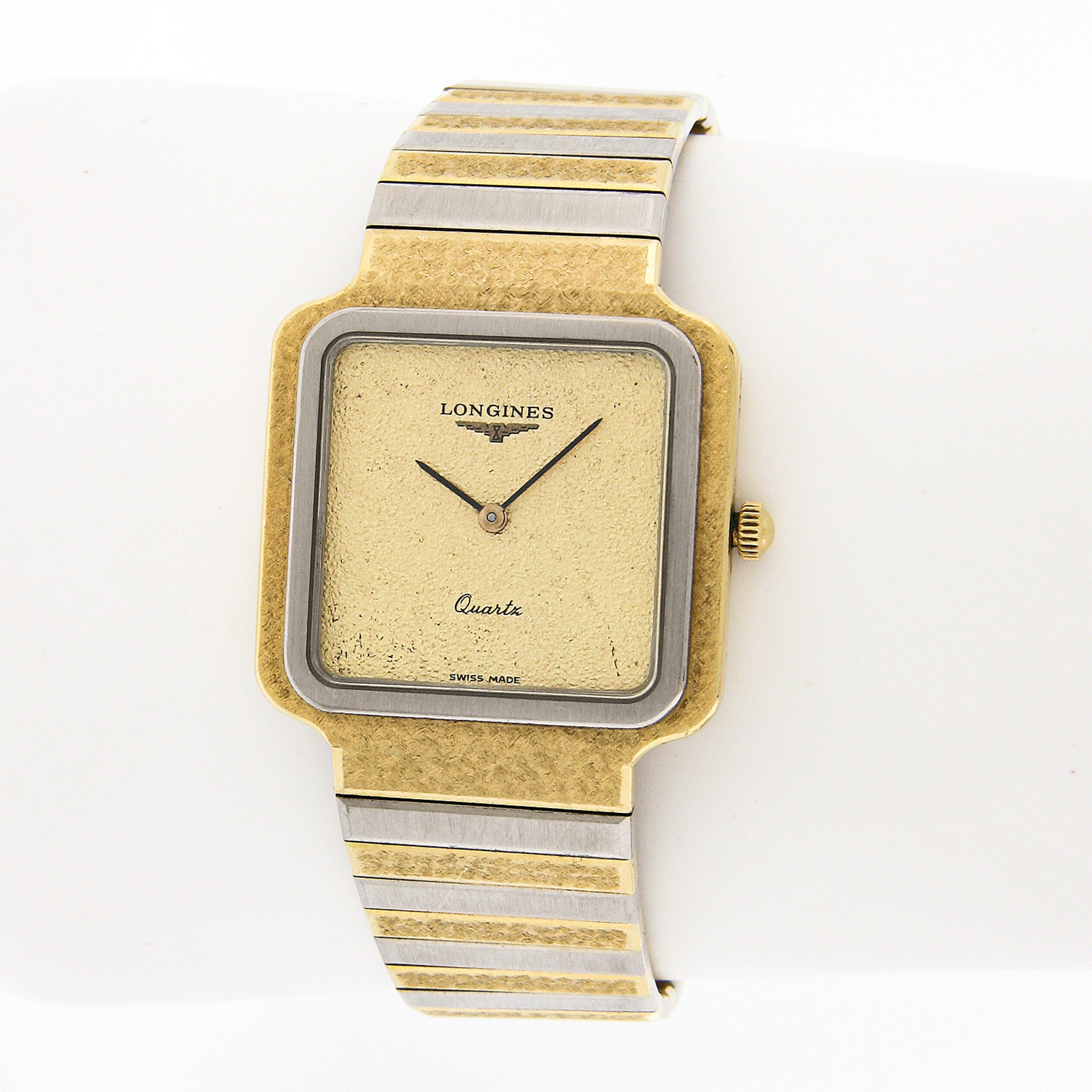 Diese elegante und luxuriöse Vintage Longines Armbanduhr verfügt über ein 28mm breites, massives 18k Goldgehäuse in quadratischer Form. Das Gehäuse hat eine einzigartige gehämmerte Oberfläche mit einer glatten und glatten Weißgoldlünette. Auch das