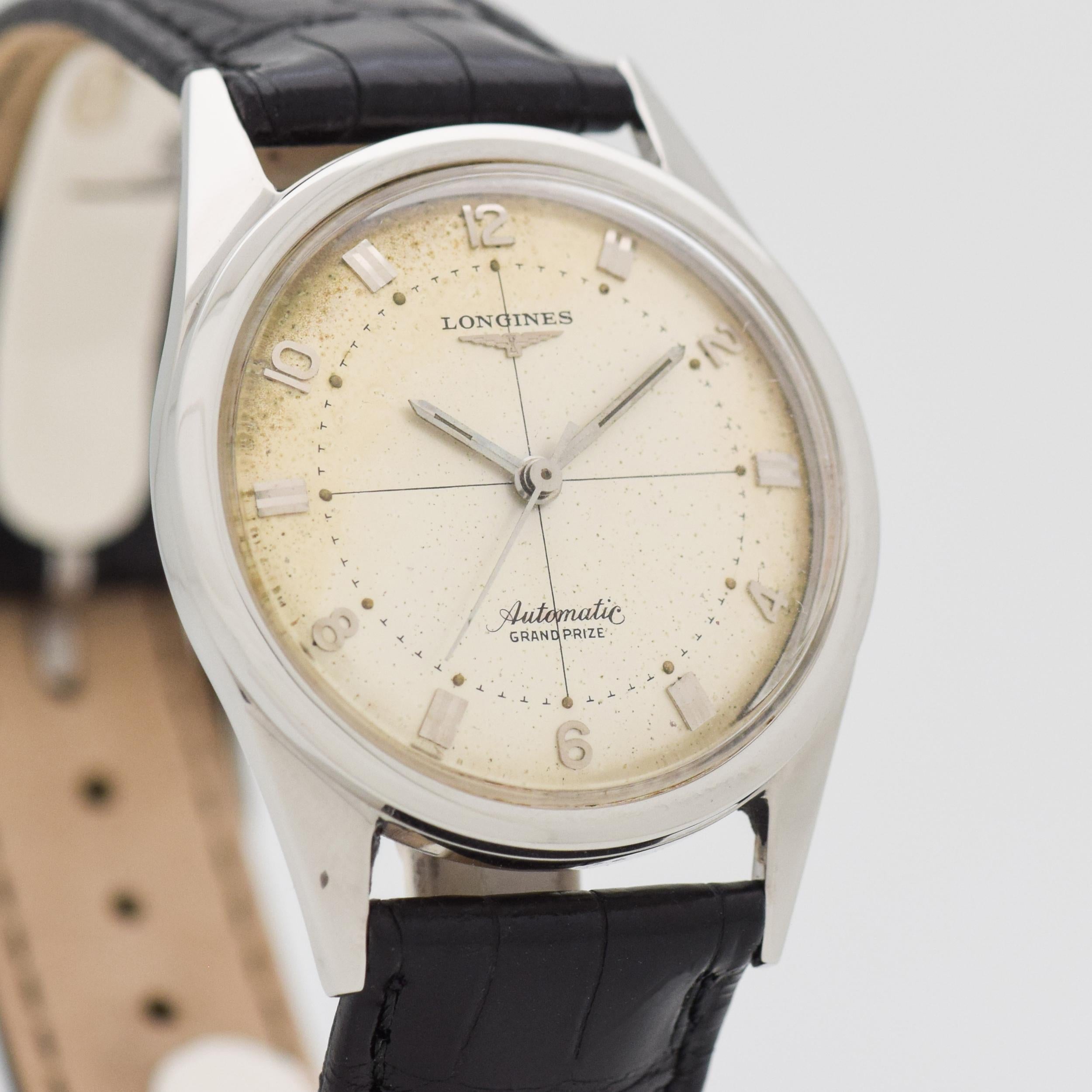 1956 Vintage Longines Grand Prize Automatic Stainless Steel Watch. Reference 2305-SW. Original, patinated silver dial with applied, silver-colored bar markers & arabic numerals. Case size, 33mm wide. Powered by a 20-jewel, automatic caliber