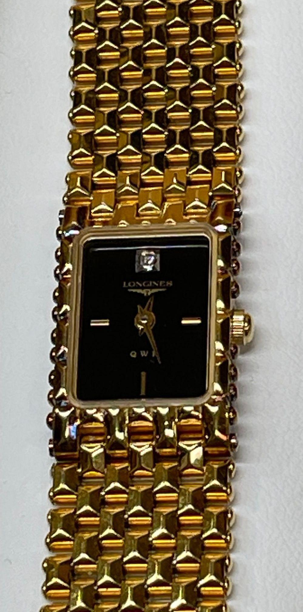 Vintage Longines QWR 030 Gold Filled Lady’s Link Bracelet Wristwatch. Black Face; Gold tone hands and hour markers. Stainless Steel back. Measuring approx. 6.75” Long. Link chain bracelet with Longines Logo on clasp closure. Deployment Buckle. New