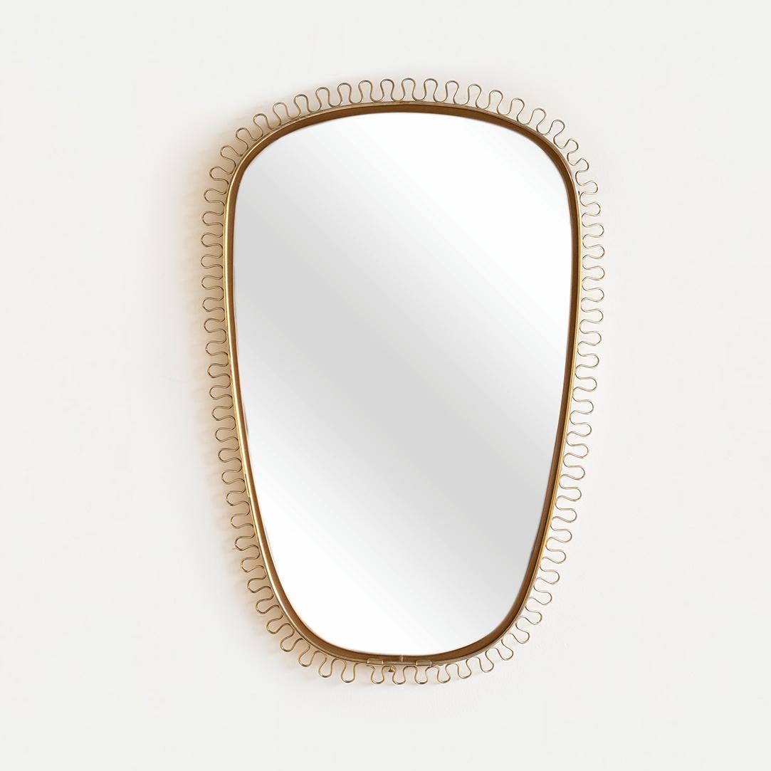 Vintage 1950's brass loop mirror by Josef Frank in Sweden. Slightly tapered shield shape frame with this brass looping encompassing mirror. Original brass finish with nice age and patina. Striking and iconic design. 

