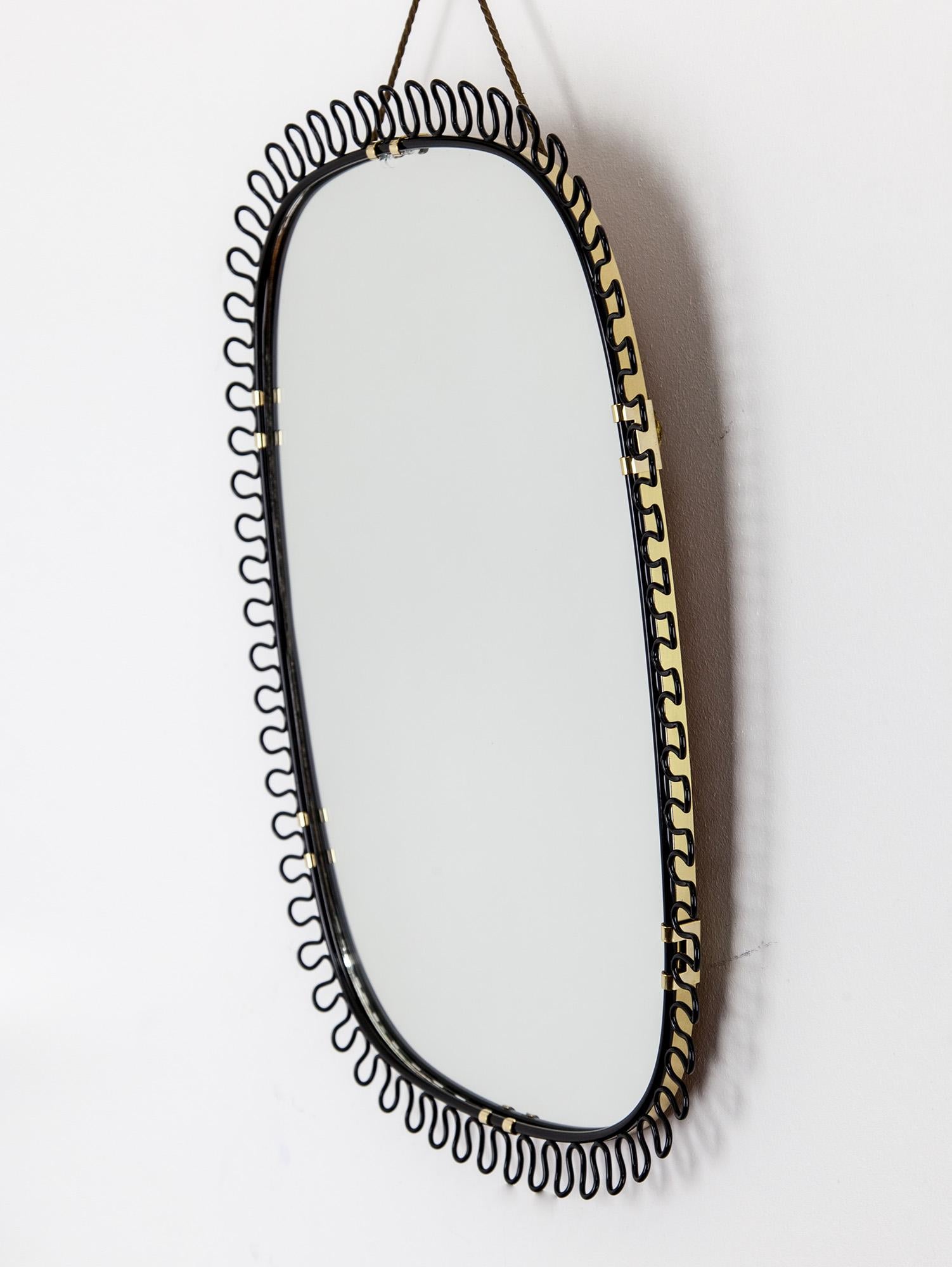 A stunning and rare sculptural black loop mirror by Josef Frank for Svenskt Tenn. The lovely continuous loop detail surrounds the mirror and contrasts against the brass frame and brass details. Hung by the original golden cord. Made in Sweden, circa