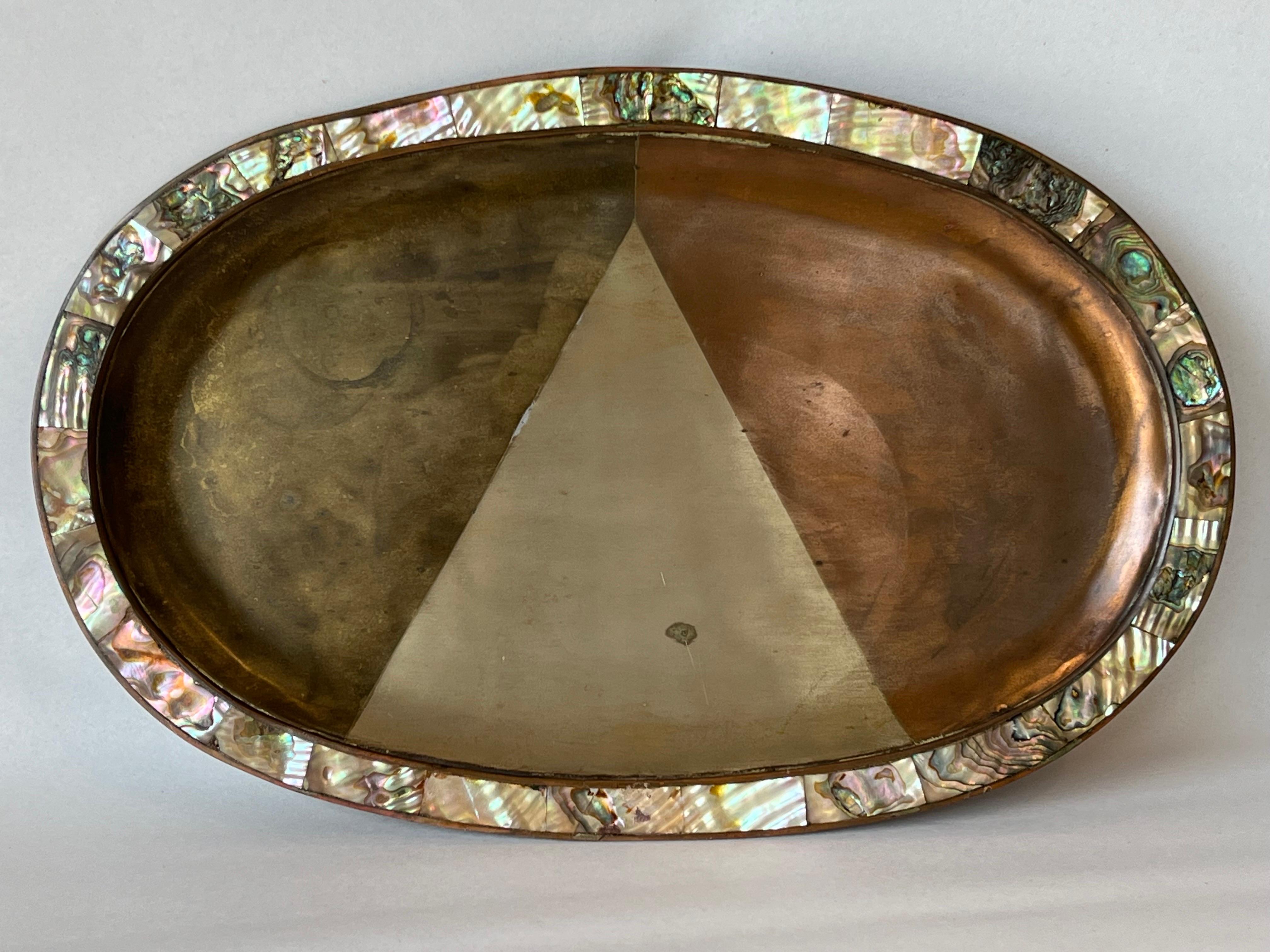 A vintage, mid century era mixed metal and shell border oval shaped tray with geometric, triangular design. This beautiful mixed metal tray is in the style of Los Castillo. This tray incorporates various metals along with a shell border with hints