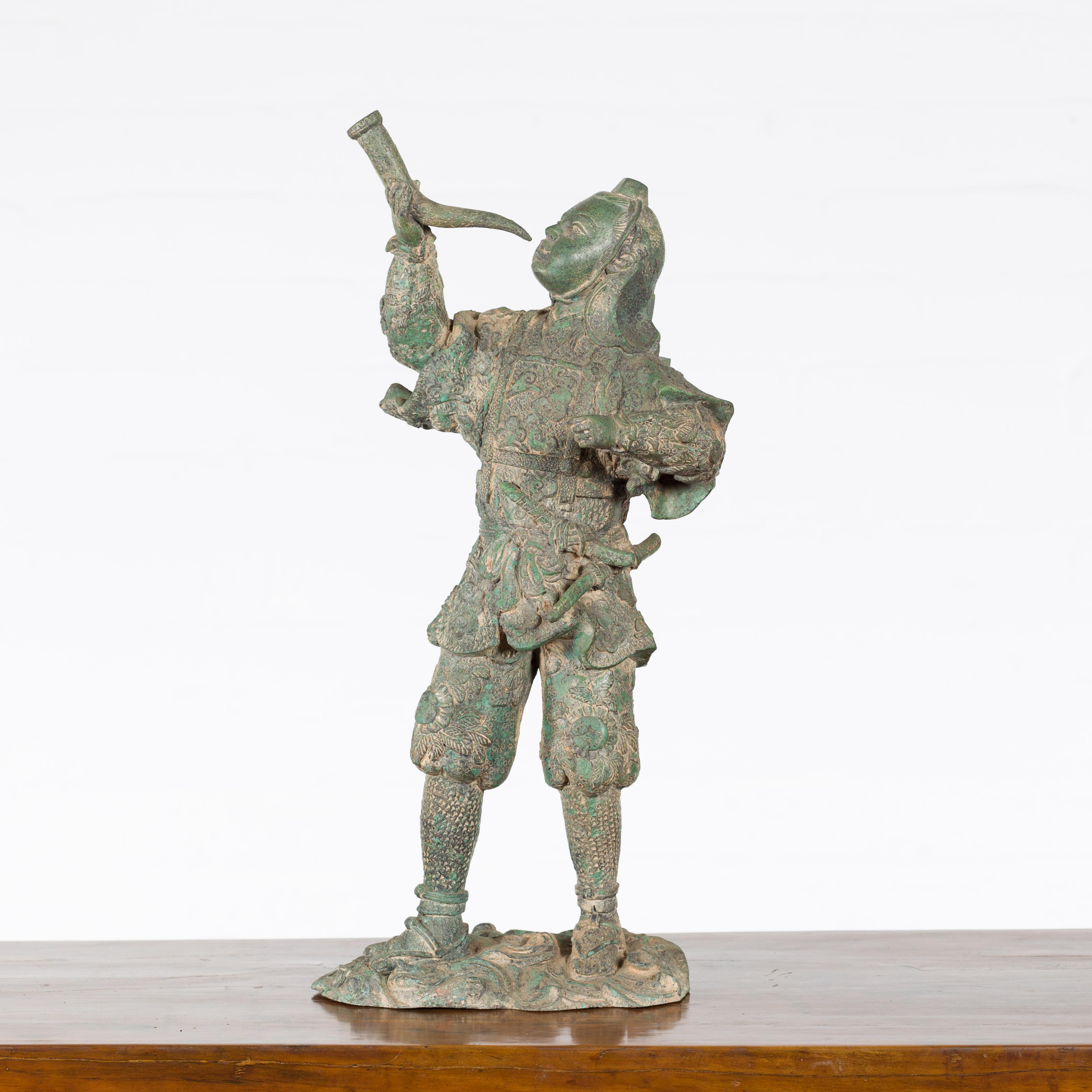 A vintage lost wax cast bronze statuette of a soldier holding a horn in verde patina. Created with the traditional technique of the lost-wax (à la cire perdue) which allows for great precision and finesse in the details, this bronze statuette