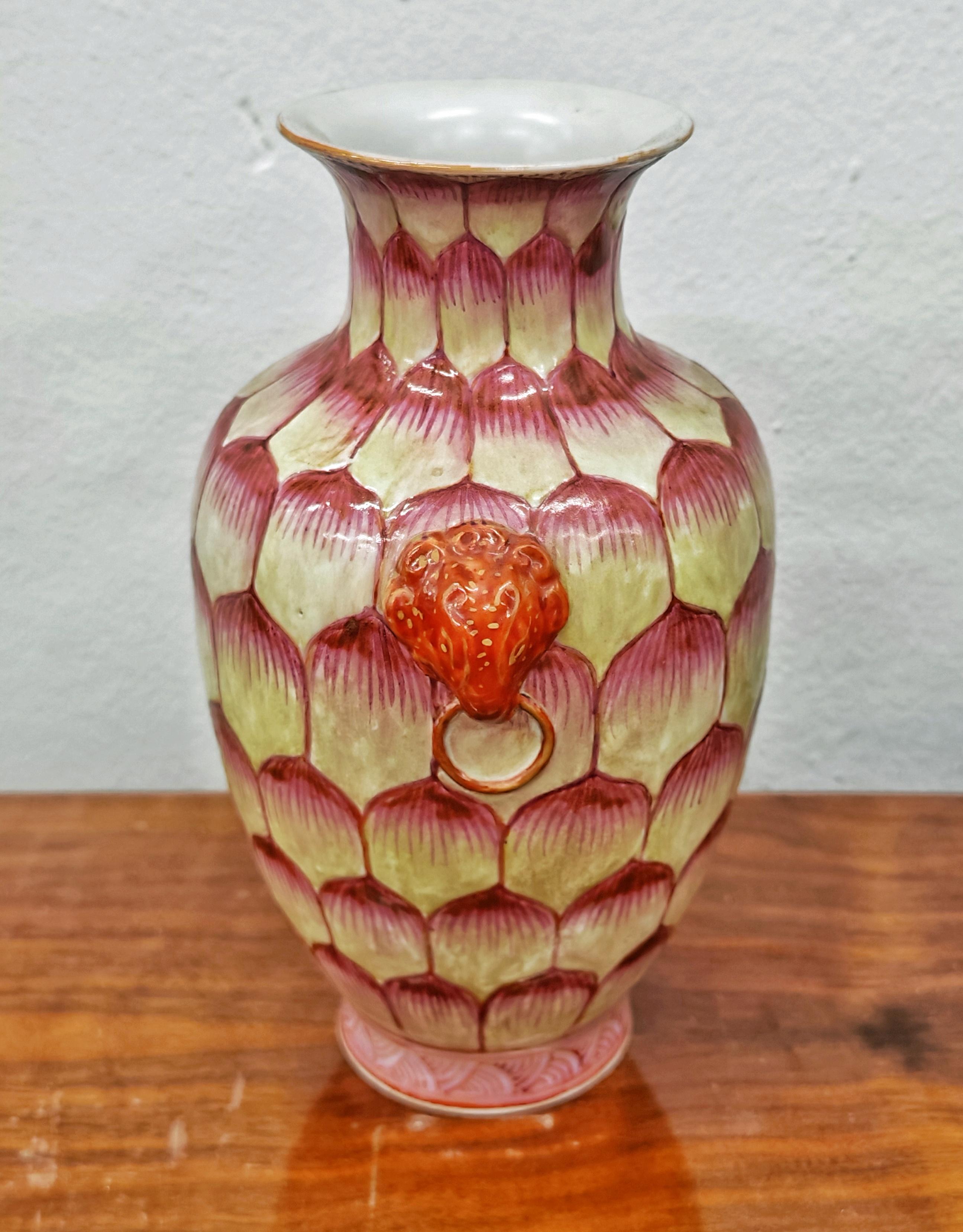 In diesem Angebot finden Sie eine wunderschöne Keramikvase, die eine Lotusknospe darstellt. Auf jeder Seite der Vase befindet sich ein Medaillon mit einem Löwenkopf. Die Vase hat wunderschöne Punk- und Elfenbeintöne, die leider nicht so gut mit der