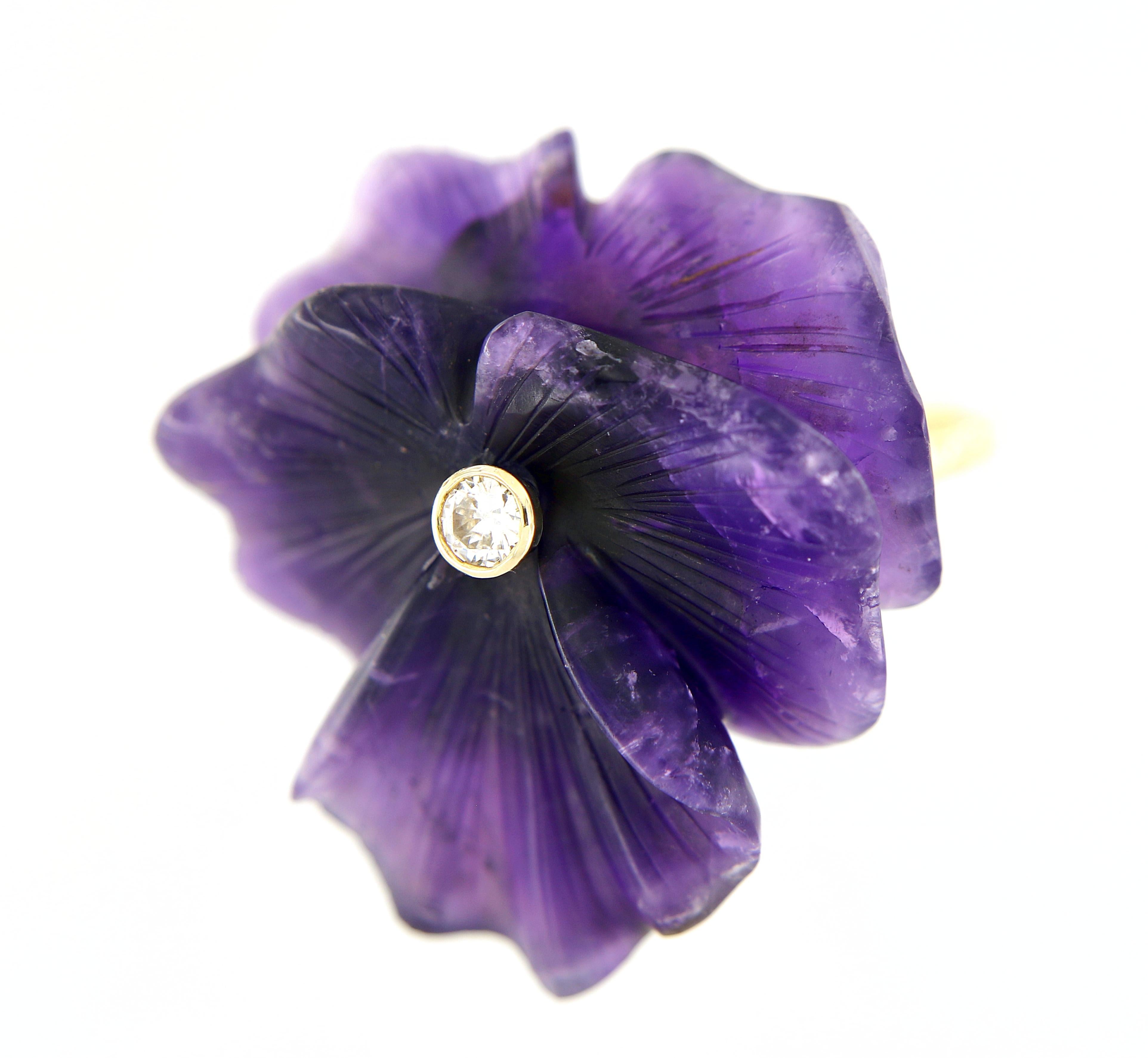 Offered here is a natural earth mined purple Amethyst carved in a lotus flower motif weighing approximately 55 carats, adorned with one natural earth mined diamond weighing approximately 0.20 carat.
Shank is 14 kt yellow gold with white