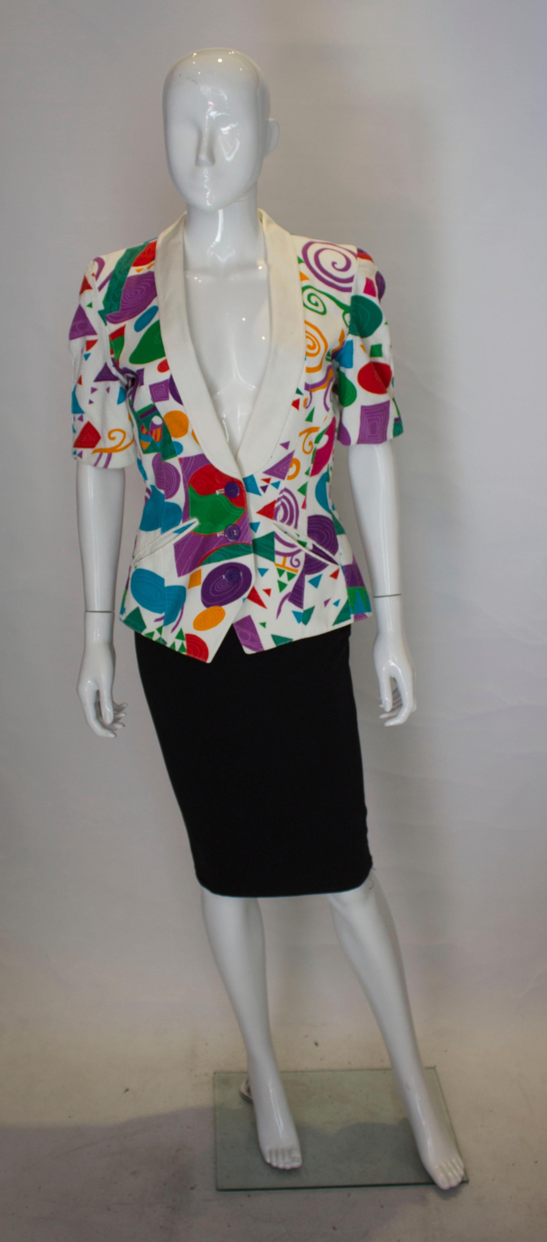 A great vintage print jacket by Louis Feraud.  The jacket has a shawl collar, short sleaves, two pockets at the front and a three button opening. It has a white background and a multicolour design, and is fully  lined.