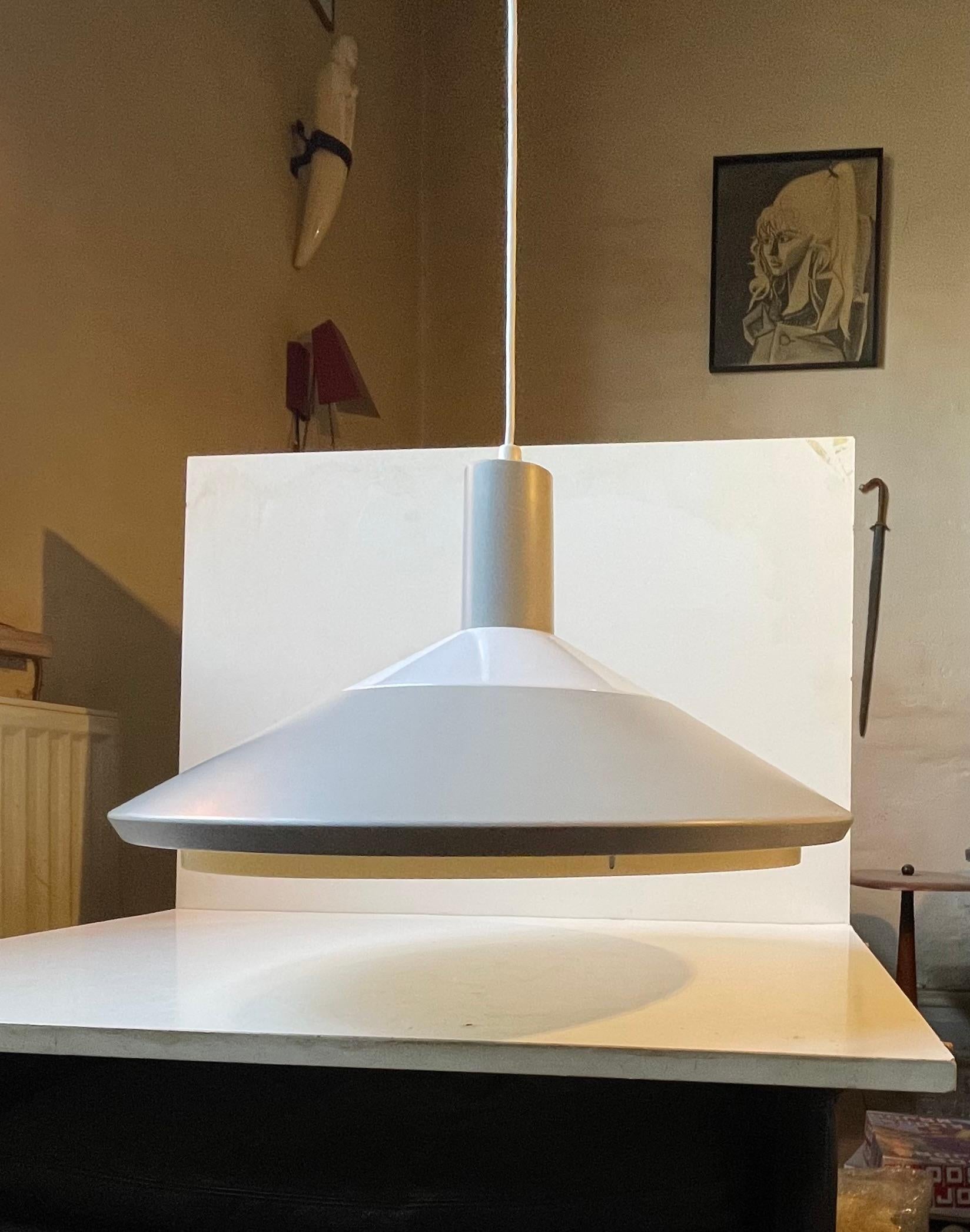 1967 von Louis Poulsen in Dänemark entworfen. Sie heißt Klassenpendel und besteht aus einem grau lackierten Aluminiumschirm mit einem Acryldiffusor/Lichtverteiler an der Unter- und Oberseite. Es hat die gleiche orangefarbene Scheibe wie PH 4 von