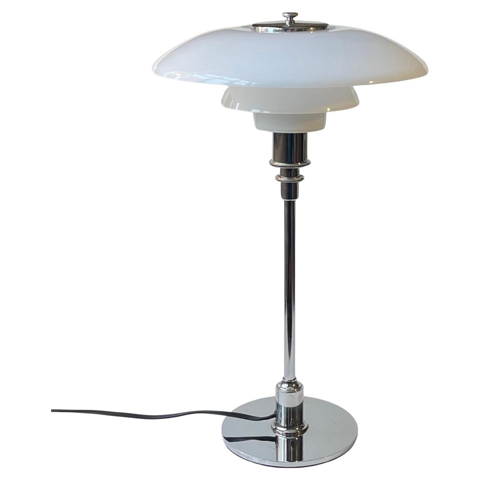 Based upon a design from the late 1920s this PH 3/2 desk lamp was relaunched by Louis Poulsen in Denmark in 1999. This particular table lamp is from that series. It features a 3-tiered shading system in white opaline glass and base, rod and details